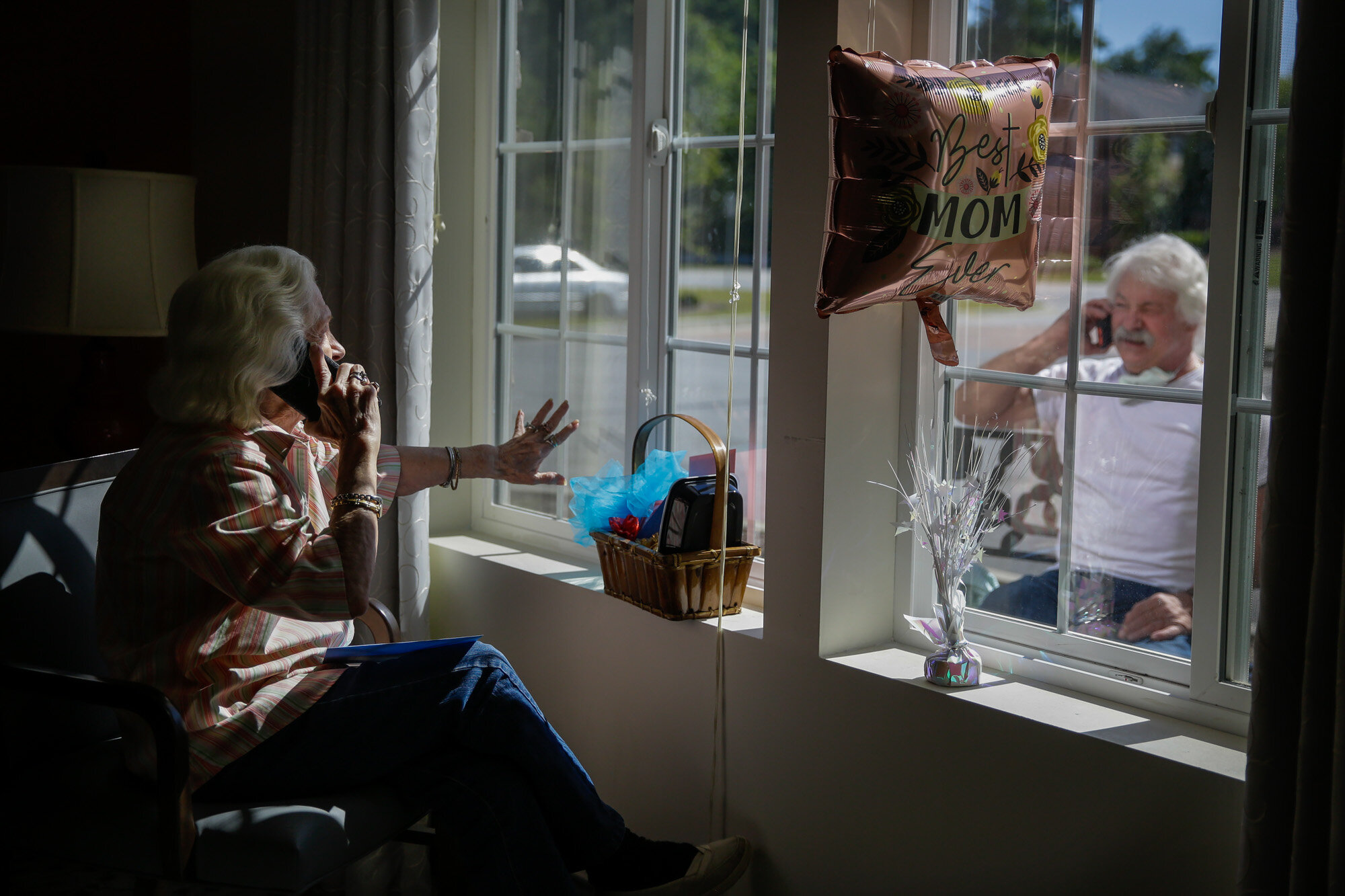Mary Faye Cochran, 86, sings "You Are My Sunshine" over the phone to her son Stacey Smith through a window on Mother’s Day, Sunday, May 10, 2020, at Provident Village at Creekside senior living in Smyrna, Ga. (AP Photo/Brynn Anderson)
