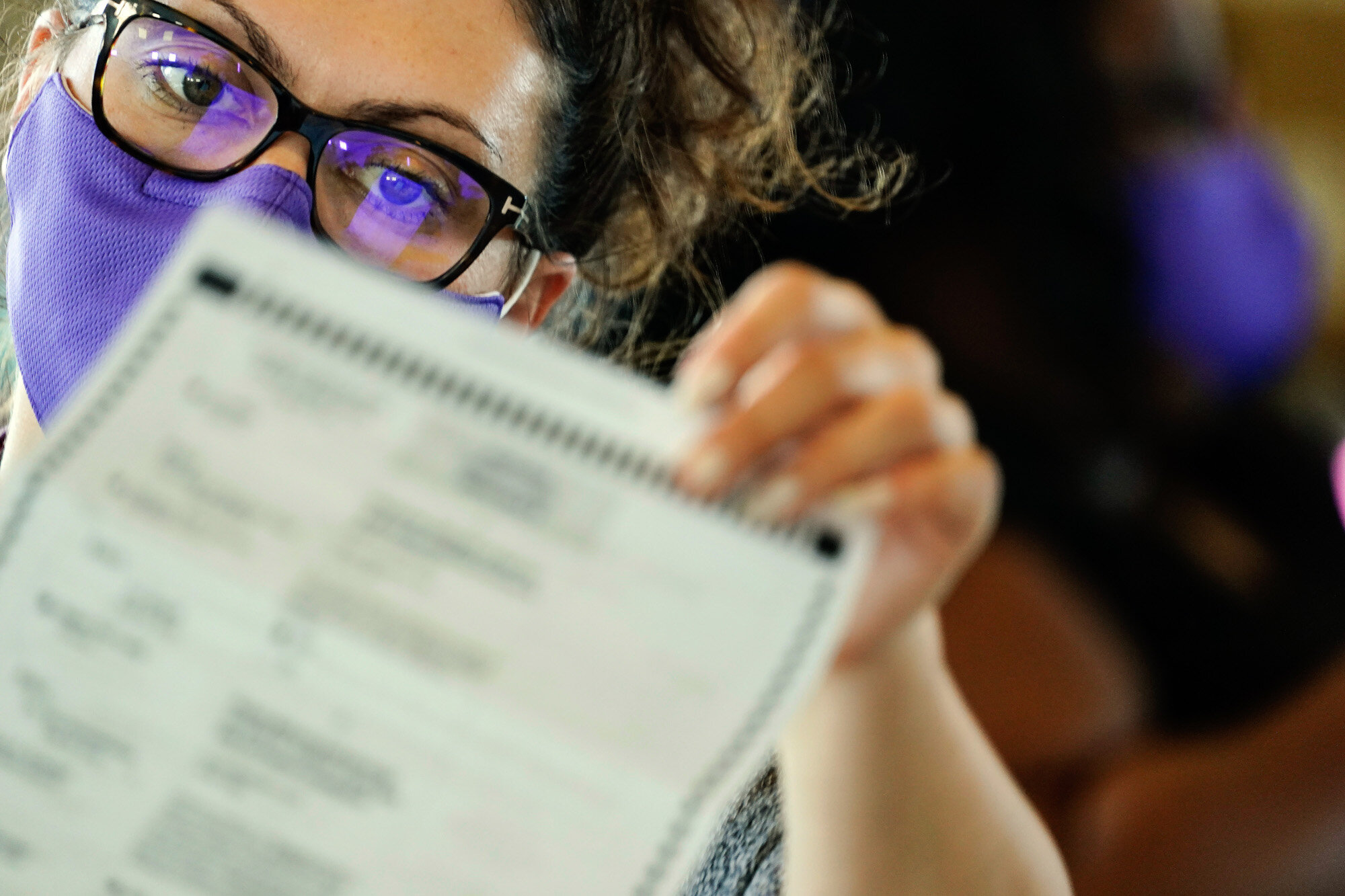 An election worker examines ballots as vote counting in the general election continues at State Farm Arena in Atlanta on Nov. 5, 2020. (AP Photo/Brynn Anderson)