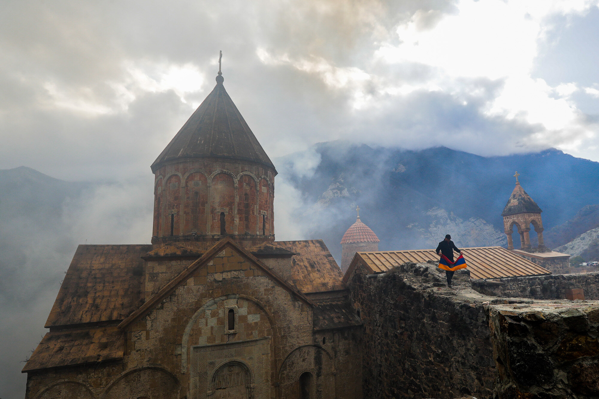 A man with an Armenian national flag visits the 12th-13th century Orthodox Dadivank Monastery on the outskirts of Kalbajar, in the separatist region of Nagorno-Karabakh, on Nov. 13, 2020. Under an agreement ending weeks of intense fighting over the Nagorno-Karabakh region, some Armenian-held territories, such as this area, will pass to Azerbaijan. (AP Photo/Sergei Grits)