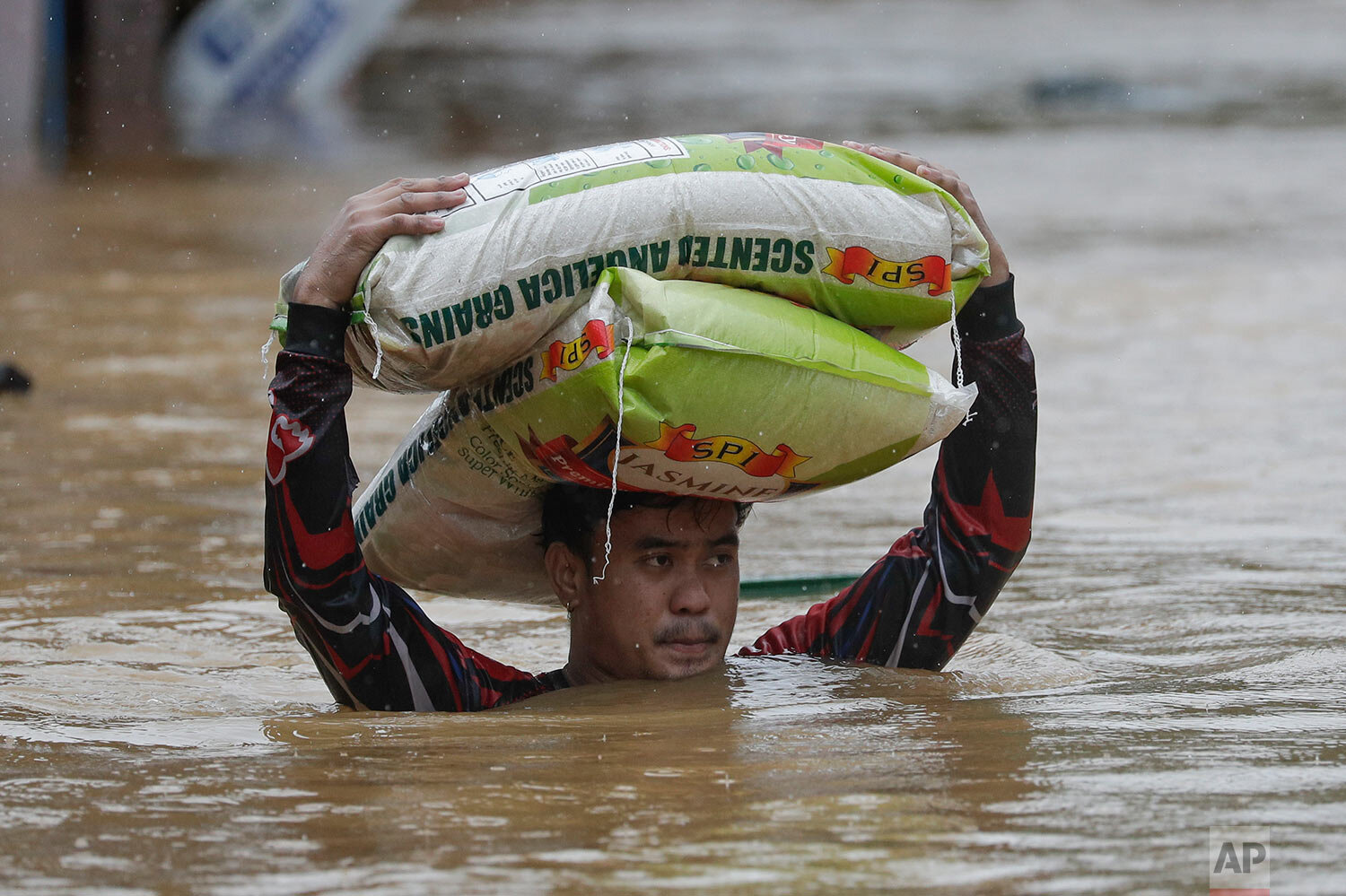  A man carries sacks of rice over floodwaters which continue to rise due to Typhoon Vamco in Marikina, Philippines on Thursday, Nov. 12, 2020.  (AP Photo/Aaron Favila) 