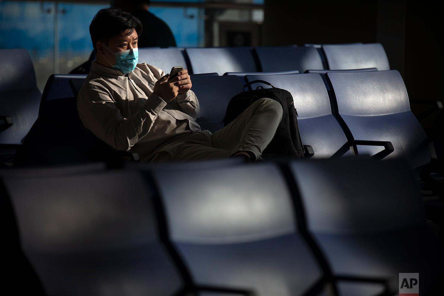  A traveler wearing a face mask to protect against the coronavirus sits at a boarding gate at the Shanghai Hongqiao International Airport in Shanghai, Friday, Nov. 6, 2020. (AP Photo/Mark Schiefelbein) 