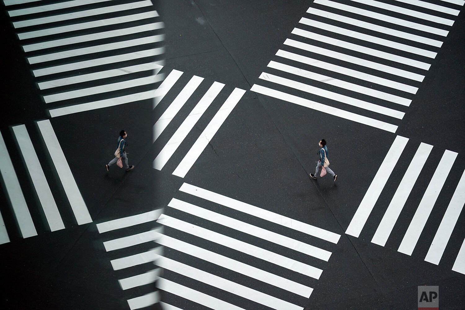  A man wearing a protective mask to help curb the spread of the coronavirus runs across a pedestrian crossing Wednesday, Nov. 25, 2020, in Tokyo.  (AP Photo/Eugene Hoshiko) 