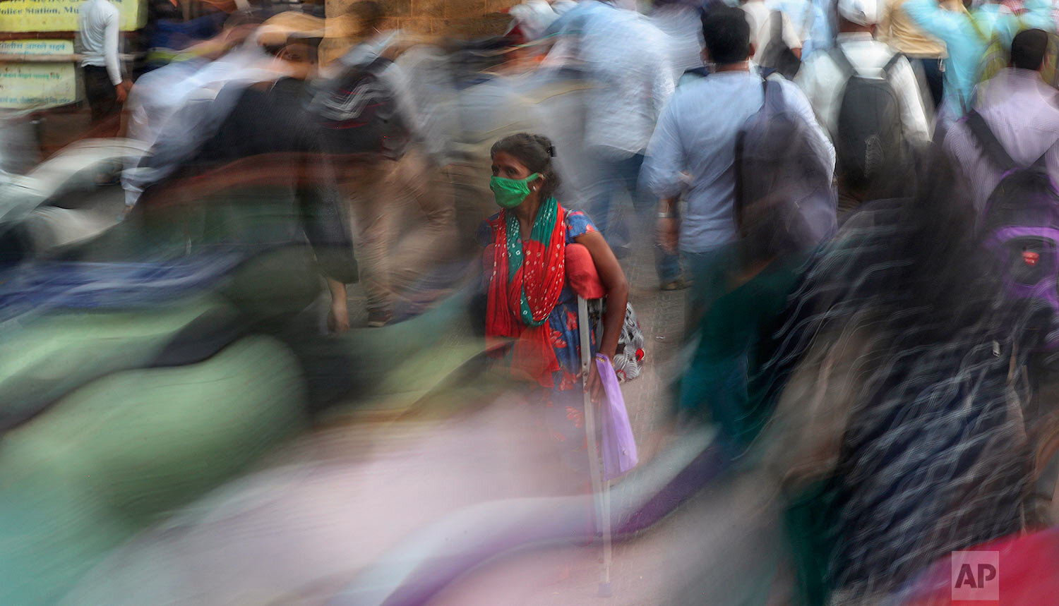  A woman asks for alms as people rush to catch the train outside the Chhatrapati Shivaji Maharaj train terminus in Mumbai, India, Monday, Nov. 9, 2020.  (AP Photo/Rafiq Maqbool) 