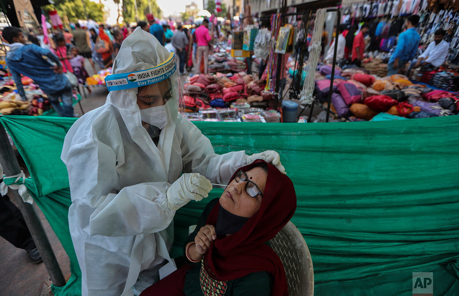  A health worker takes a nasal swab sample of a woman to test for COVID-19 at a facility erected in a market in Ahmedabad, India, Tuesday, Nov. 17, 2020.  (AP Photo/Ajit Solanki) 