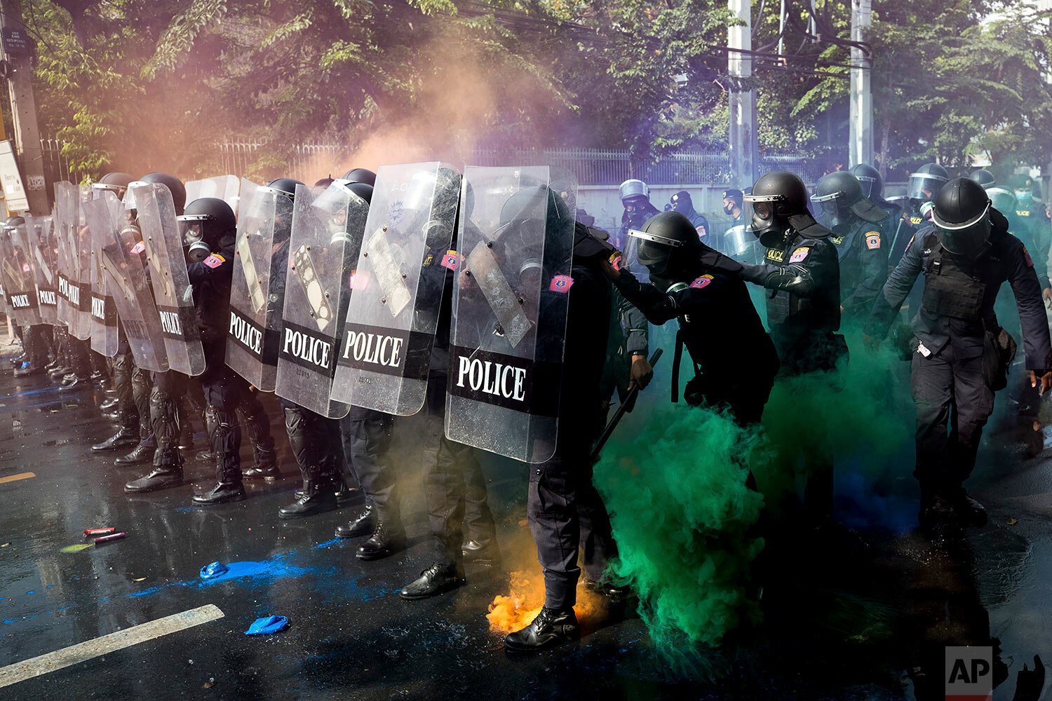  Police in riot gear stand in formation as pro-democracy protesters throw smoke bombs near the Parliament in Bangkok, Tuesday, Nov. 17, 2020. (AP Photo/Wason Wanichakorn) 