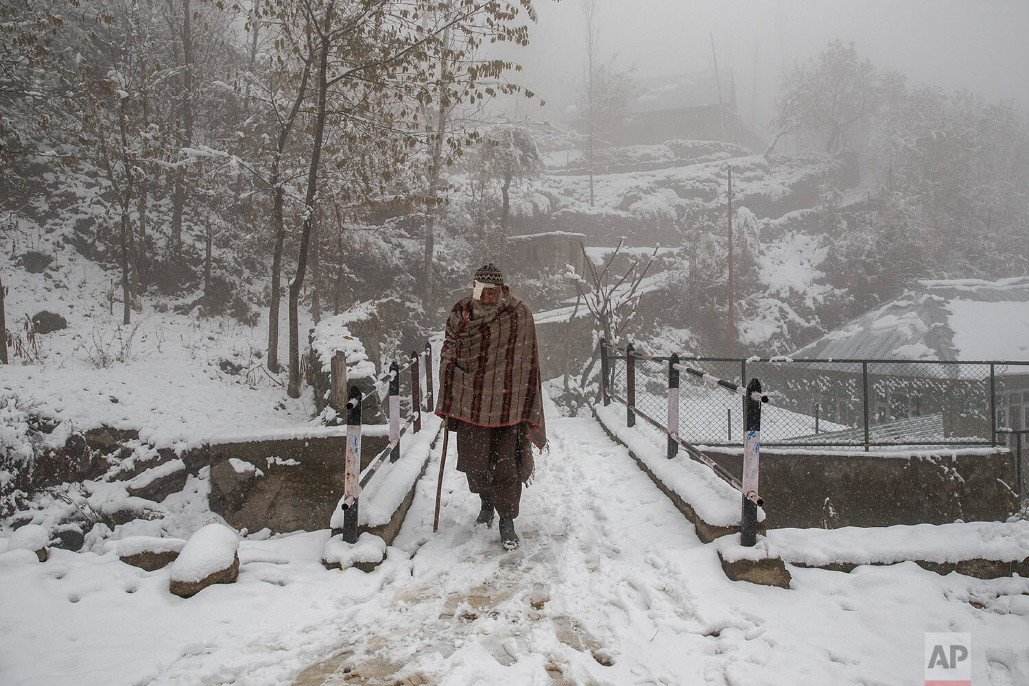  An elderly Kashmir villager walks on a snow covered road during the season's first snowfall on the outskirts of Srinagar, Indian controlled Kashmir, Monday, Nov. 23, 2020. (AP Photo/Dar Yasin) 