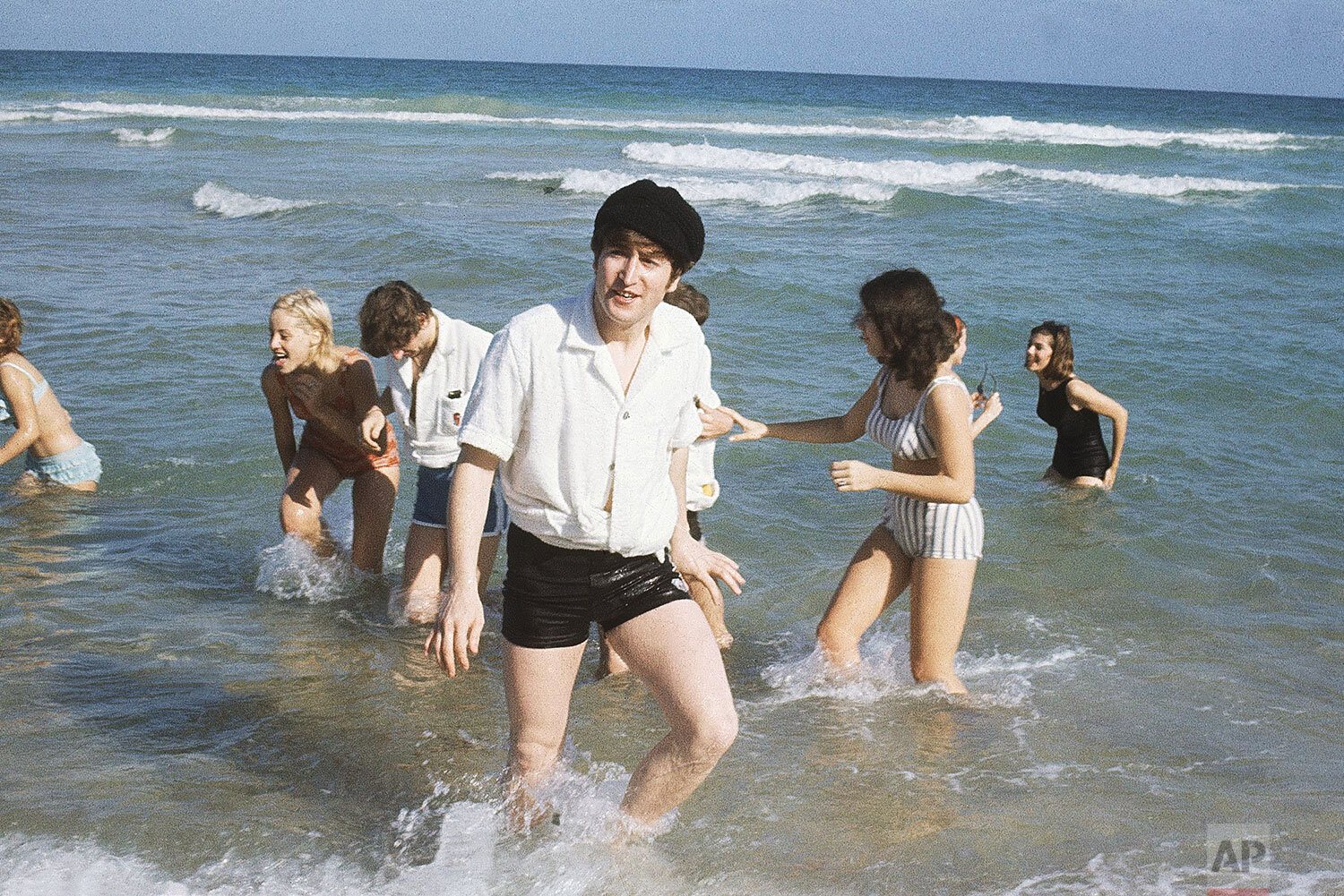  John Lennon of the Beatles emerges from the surf at Miami, Florida in February 1964. In background, left, is Ringo Starr with an unidentified woman. (AP Photo) 