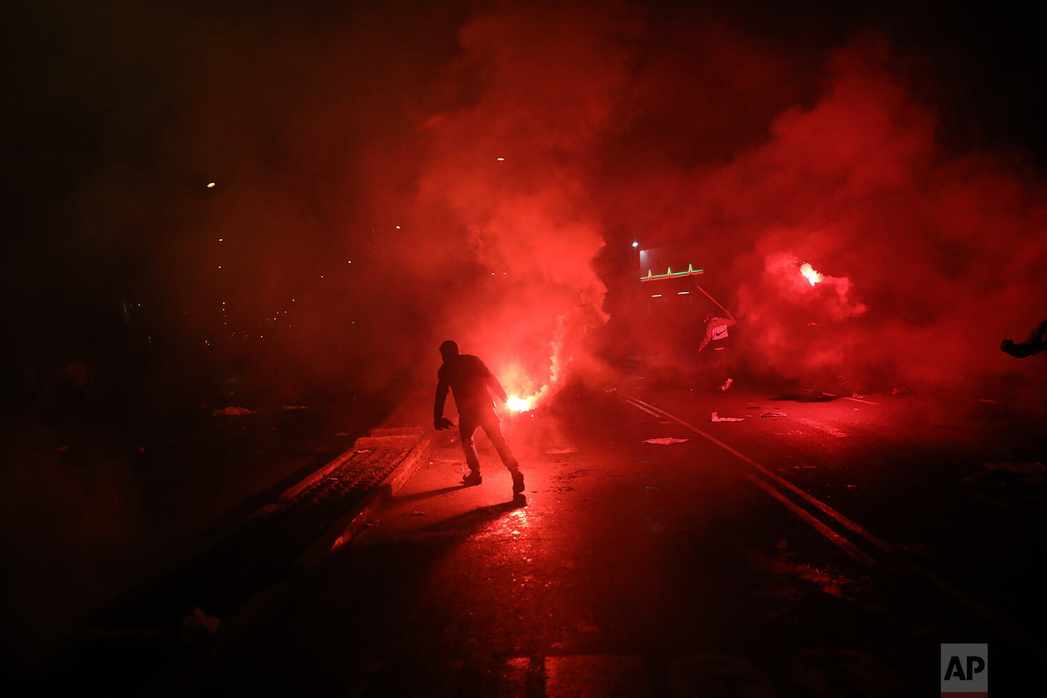  A protester holds a flare amid tear gas launched by police to disperse protesters who tried to march to Congress in a demonstration against the removal of President Martin Vizcarra, in Lima, Peru, Thursday, Nov. 12, 2020. (AP Photo/Rodrigo Abd) 