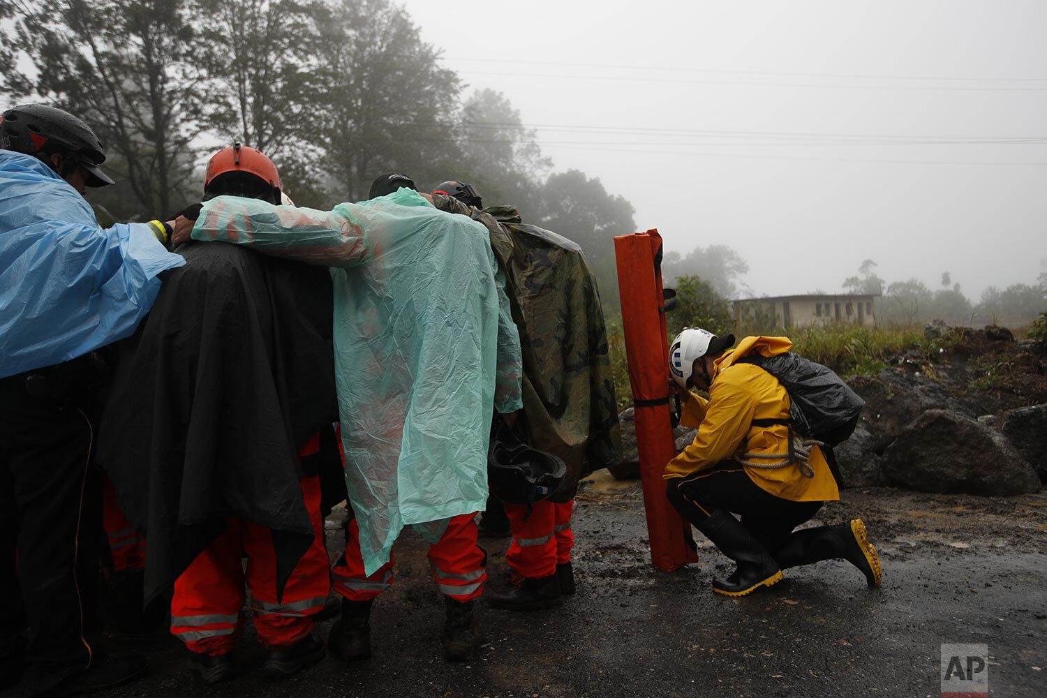  Volunteer firefighters huddle in prayer before beginning a search and rescue operation for people believed buried by a rain-fueled landslide in San Cristobal Verapaz, Saturday, Nov. 7, 2020, in the aftermath of Hurricane Eta. (AP Photo/Moises Castil