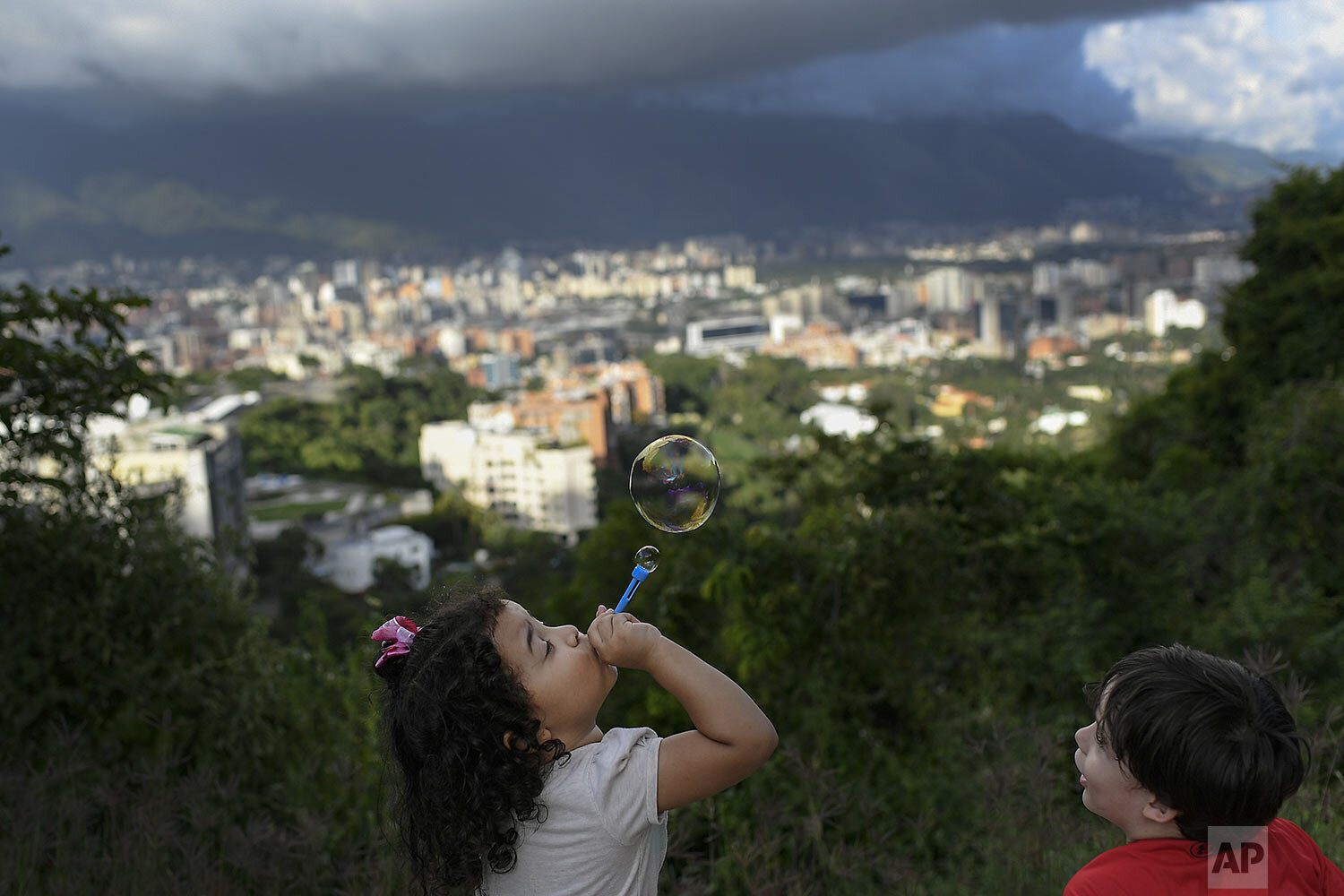  A child blows soap bubbles at Valle Arriba viewpoint overlooking Caracas, Venezuela, Sunday, Nov. 8, 2020. (AP Photo/Matias Delacroix) 
