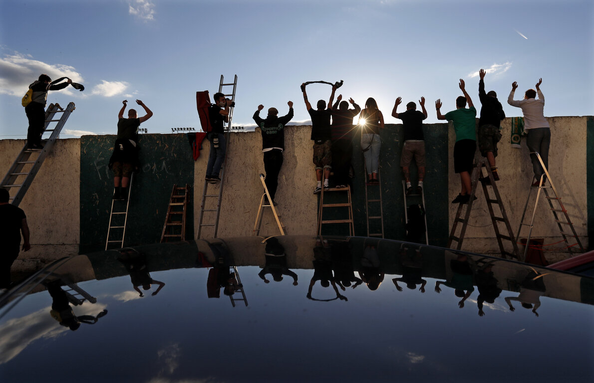  Fans, standing on ladders from behind the fence, celebrate a goal as they watch a Czech first division match between Bohemians Prague and Zlin in Prague, Czech Republic, Sunday, Oct. 4, 2020. Amid restrictive measures that limit the number of soccer