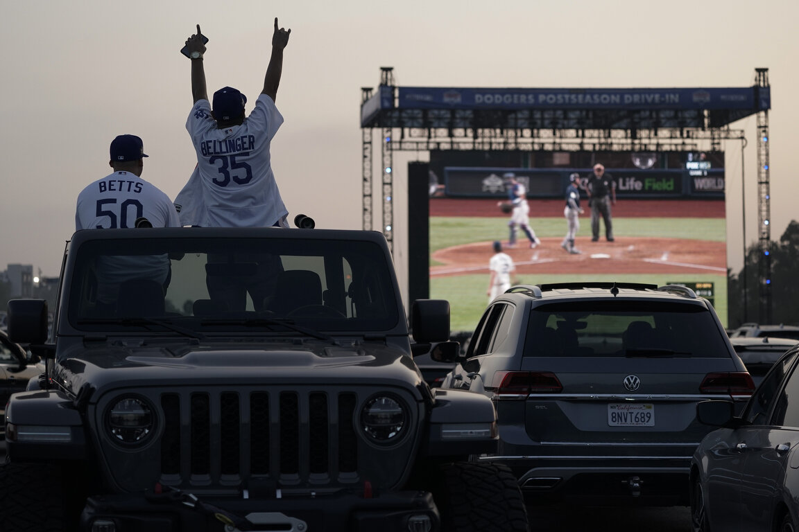  Mike Kim, left, and Jacob Zelaya cheer in their vehicle outside Dodger Stadium while watching the television broadcast of Game 1 of the 2020 World Series between the Los Angeles Dodgers and the Tampa Bay Rays in Tuesday, Oct. 20, 2020, in Los Angele