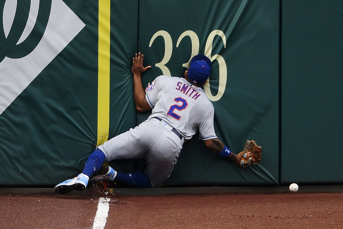  New York Mets' Dominic Smith smashes into the outfield wall while chasing a fly ball that went for an inside-the-park home run by Washington Nationals' Andrew Stevenson during the fifth inning of the first baseball game of a doubleheader, Saturday, 