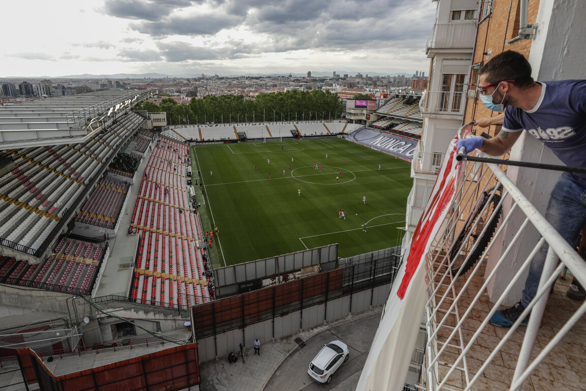  A man on a balcony watches the second-division game between Rayo Vallecano and Albacete in Madrid, Spain, Wednesday, June 10, 2020. The Spanish league resumes this week, more than three months after it was suspended because of the pandemic. (AP Phot