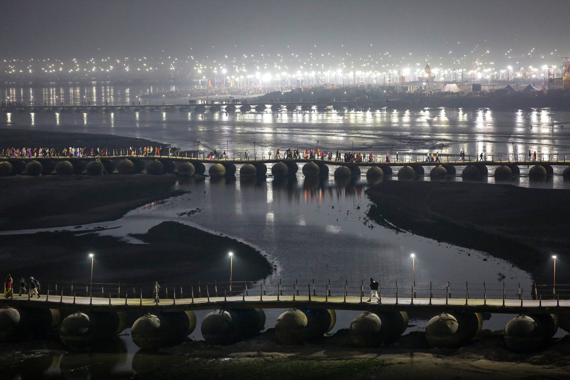 Indian Hindu pilgrims walk through a pontoon bridge before dawn at Sangam, the confluence of rivers Ganges, Yamuna, and mythical Saraswati during Magh Mela, a festival that attracts millions of pilgrims every year, in Prayagraj, in the northern Indian state of Uttar Pradesh on Jan. 30, 2020. (AP Photo/Altaf Qadri)