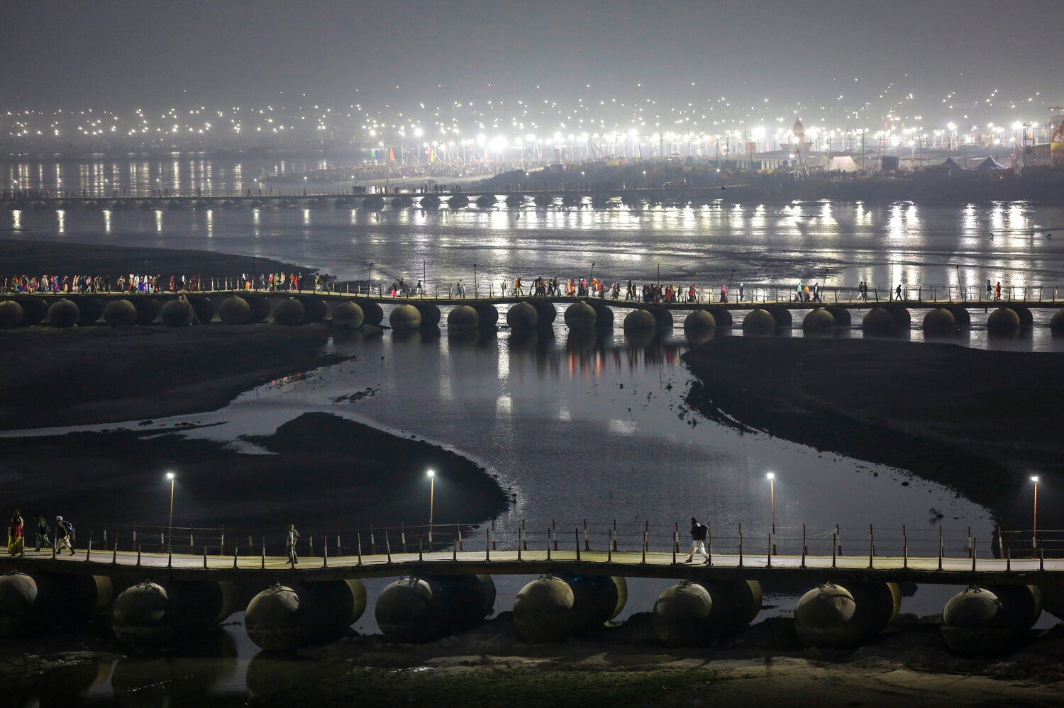  Indian Hindu pilgrims walk through a pontoon bridge before dawn at Sangam, the confluence of rivers Ganges, Yamuna, and mythical Saraswati during Magh Mela, a festival that attracts millions of pilgrims every year, in Prayagraj, in the northern Indian state of Uttar Pradesh on Jan. 30, 2020. (AP Photo/Altaf Qadri) 