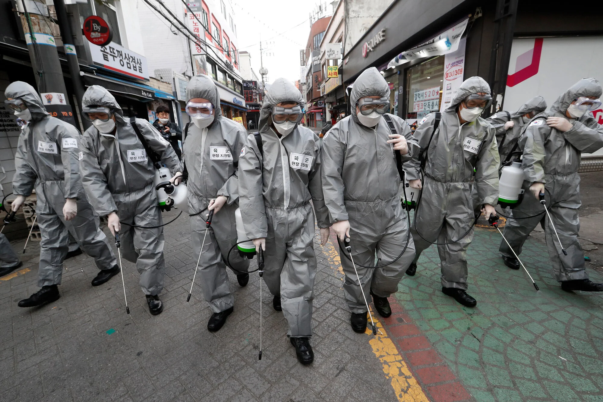 Army soldiers wearing protective suits spray disinfectant as a precaution against the coronavirus at a shopping street in Seoul, South Korea, on March 4, 2020. (AP Photo/Ahn Young-joon)
