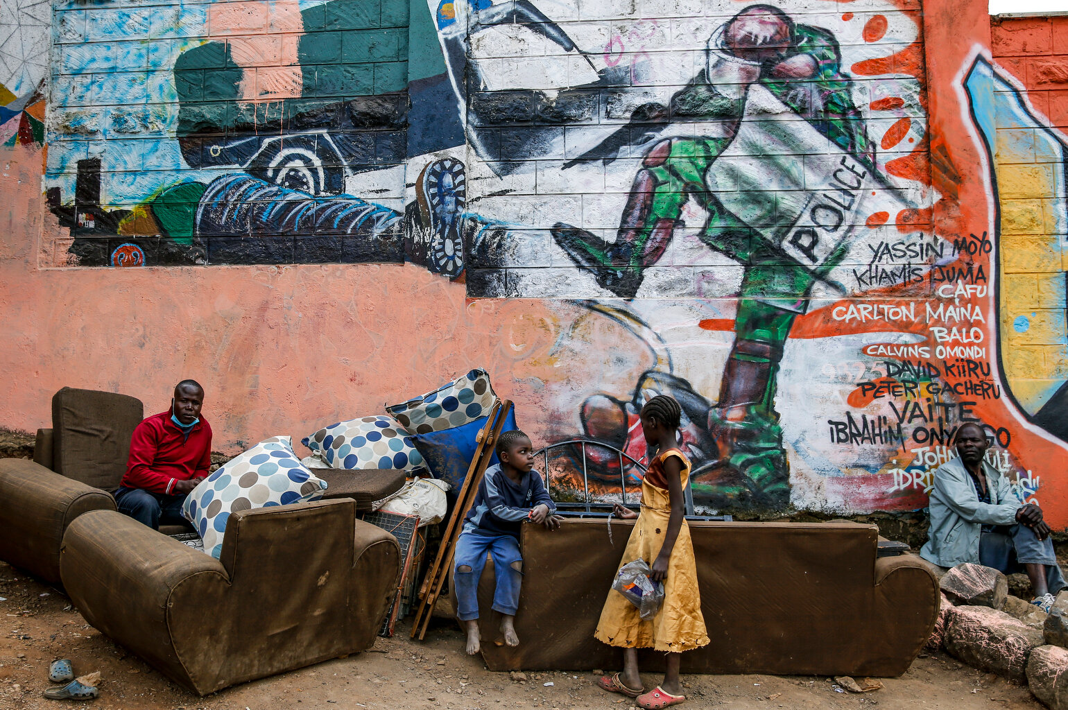  Kenyan children and men are photographed in front of a new mural painted this week showing an incident in 2016 when a Kenyan riot policeman repeatedly kicked a protester as he lay in the street, as a message about police brutality in Kenya and prote