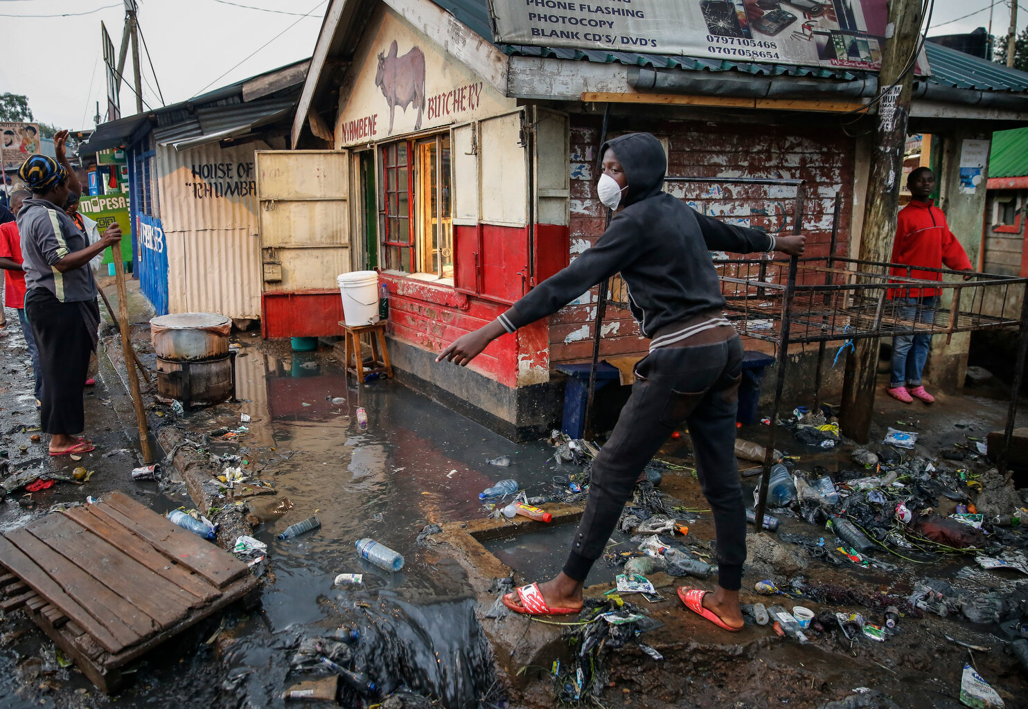  A boy wears a mask as a preventative measure against the spread of the new coronavirus, as he navigates a flood of water mixed with garbage following heavy rains, in the Kibera slum, or informal settlement, of Nairobi, Kenya, Thursday, March 26, 202