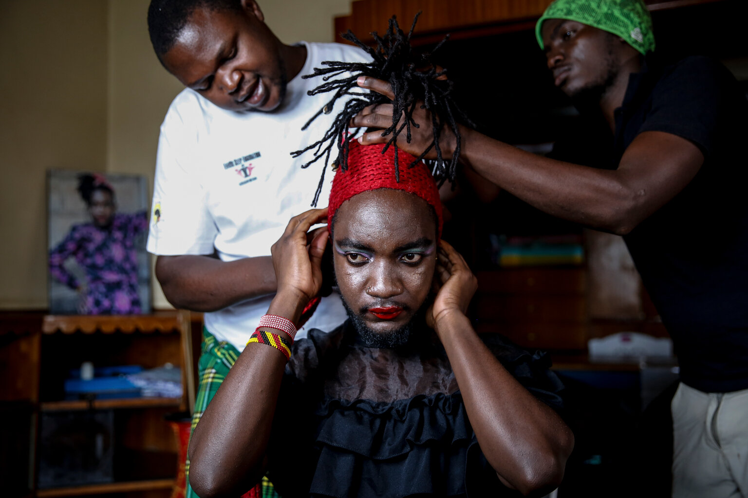  Raymond Brian, center, a Ugandan refugee and a nonconforming gender person who also goes by the name of "Mother Nature" has his make-up done by fellow Ugandan refugees Kasaali Brian, left, and Chris Wasswa, right, at a house that serves as a shelter