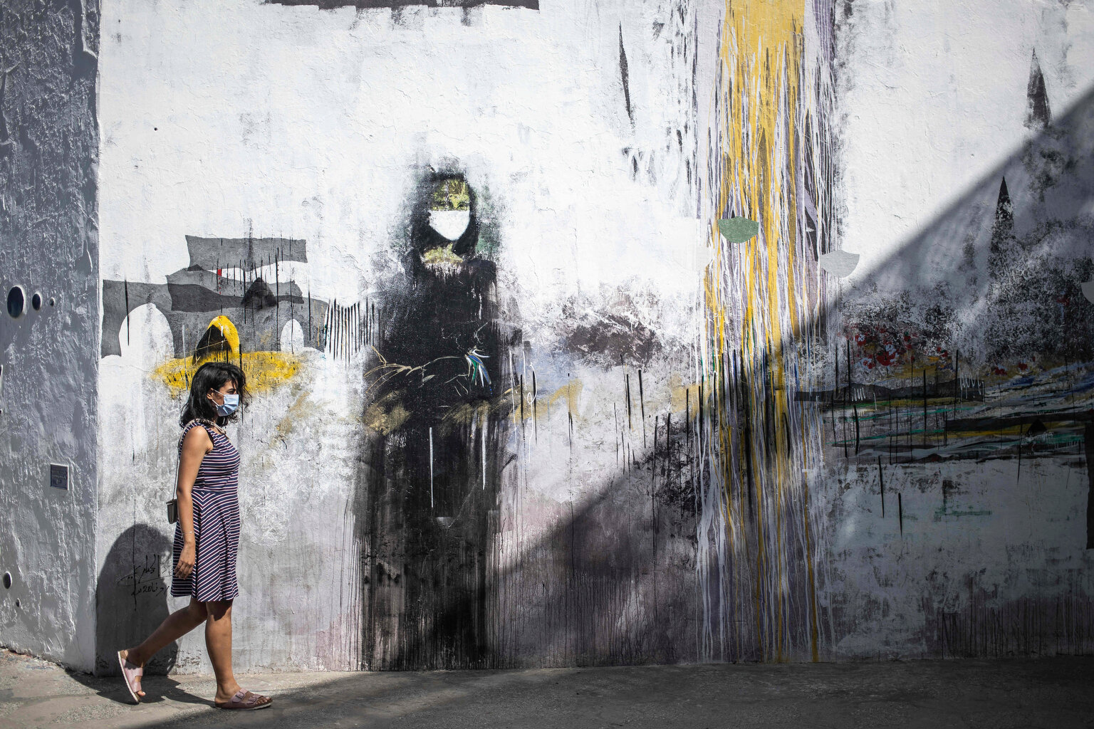  A woman wearing a face mask to prevent the spread of coronavirus walks past a mural of a mask-wearing Mona Lisa, in the Medina of Asilah, northern Morocco, Saturday, Sept. 19, 2020. The town is known for its well-preserved ramparts which were built 