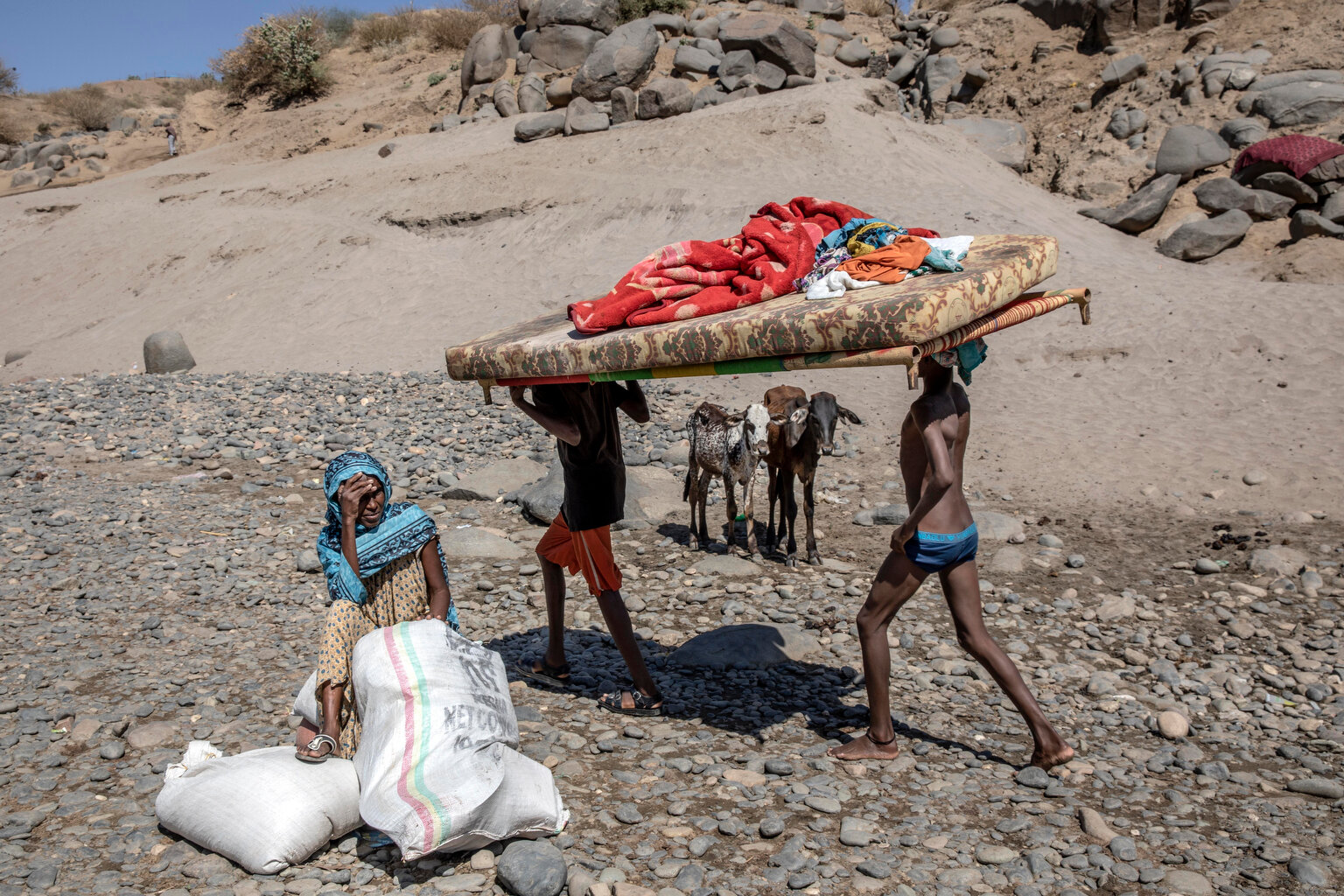  Tigray refugees who fled the conflict in the Ethiopia's Tigray carry their furniture on the banks of the Tekeze River on the Sudan-Ethiopia border, in Hamdayet, eastern Sudan, Tuesday, Dec. 1, 2020. The elderly woman waits for her family with their 