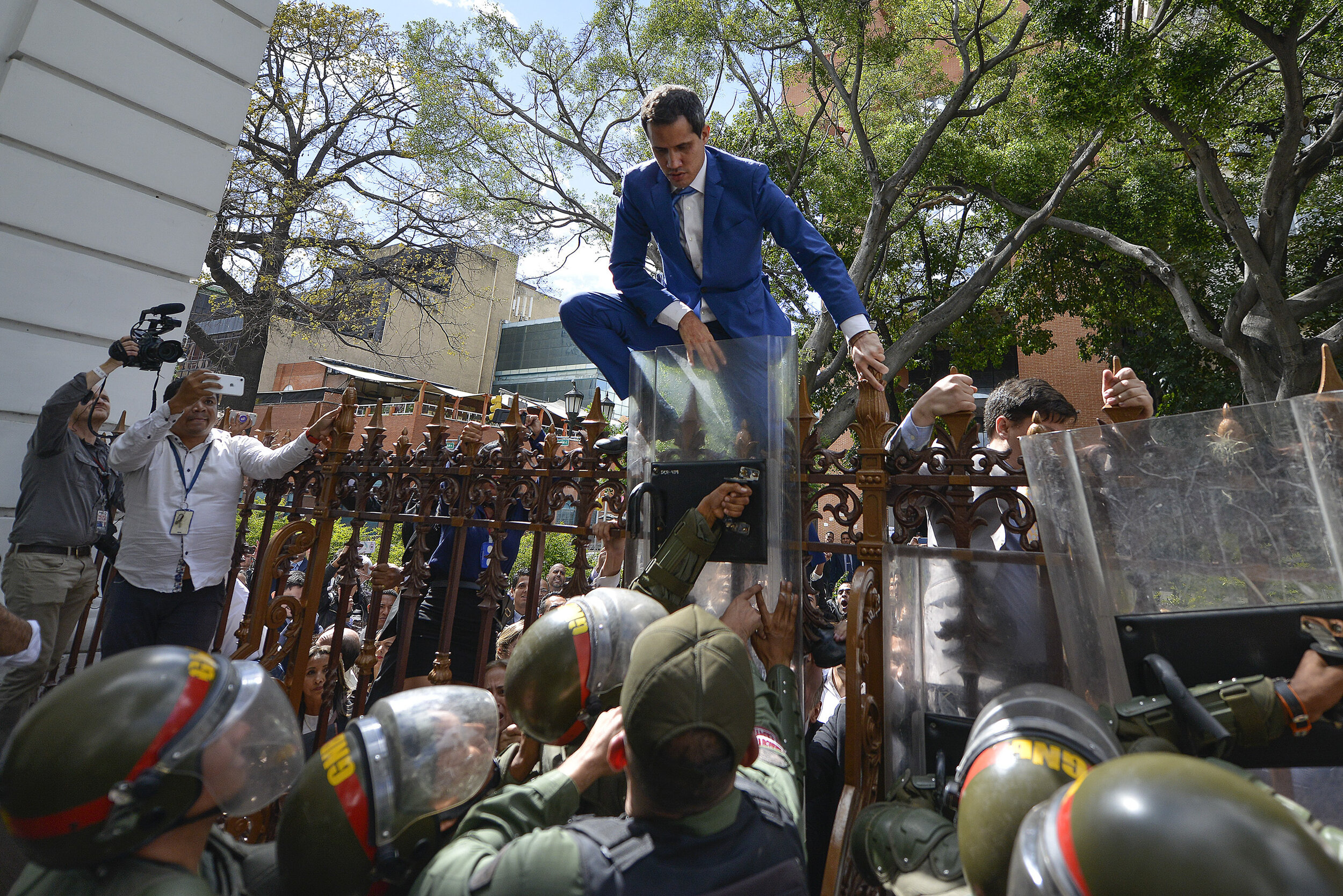  National Assembly President Juan Guaido, Venezuela's opposition leader, climbs the fence in a failed attempt to enter the Assembly compound as he and other opposition lawmakers are blocked from entering a session to elect the body's new leadership i