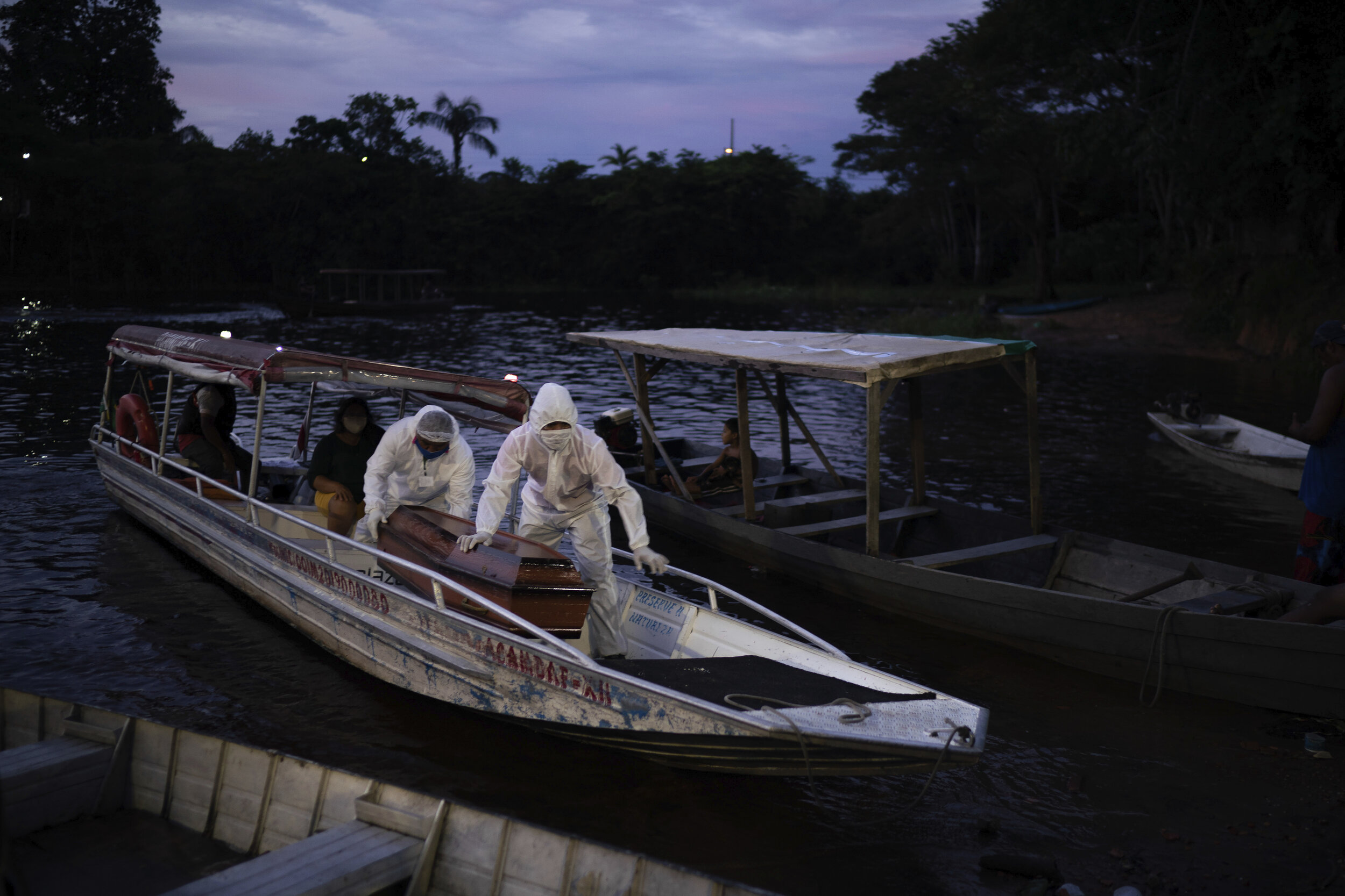  SOS Funeral workers transport by boat a remains of an 86-year-old woman who is suspected of dying of COVID-19 in her river-side community near Manaus, Brazil, May 14, 2020. (AP Photo/Felipe Dana) 