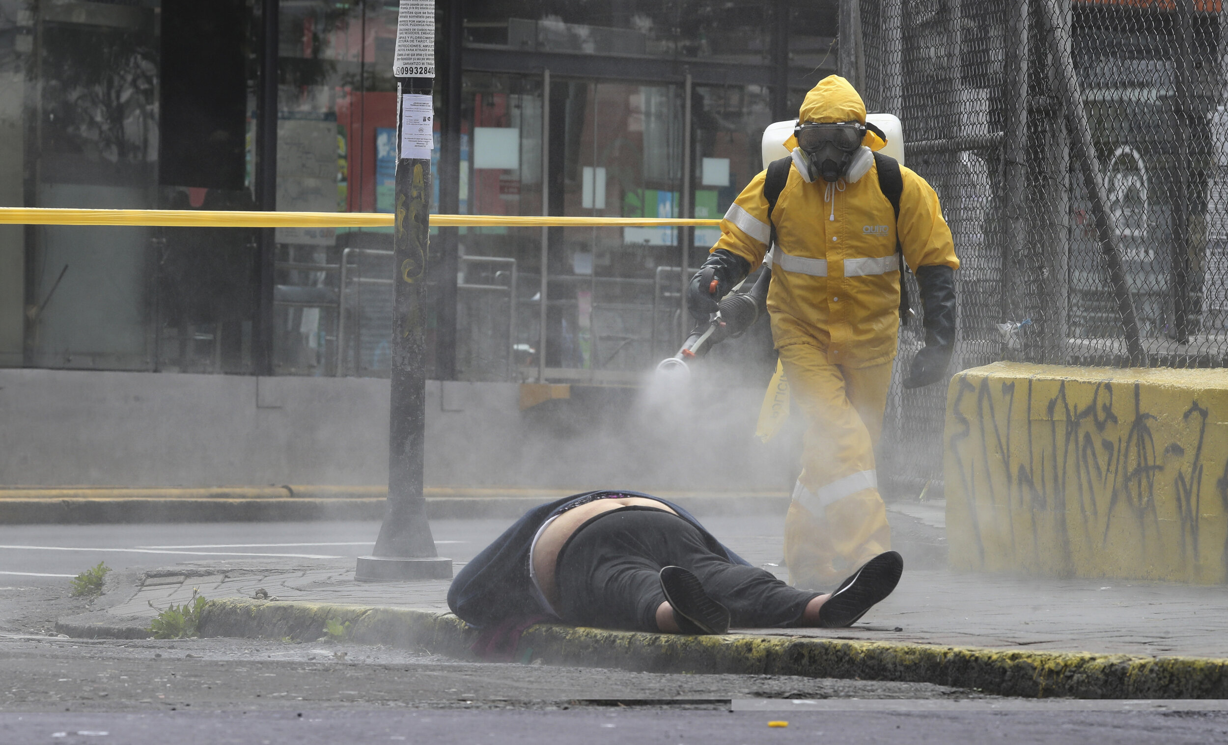  A city forensic worker sprays disinfectant on the body of a woman who died in the street in Quito, Ecuador, Thursday, May 14, 2020. Forensics conducted a COVID-19 rapid test and said the woman tested negative. (AP Photo/Dolores Ochoa) 