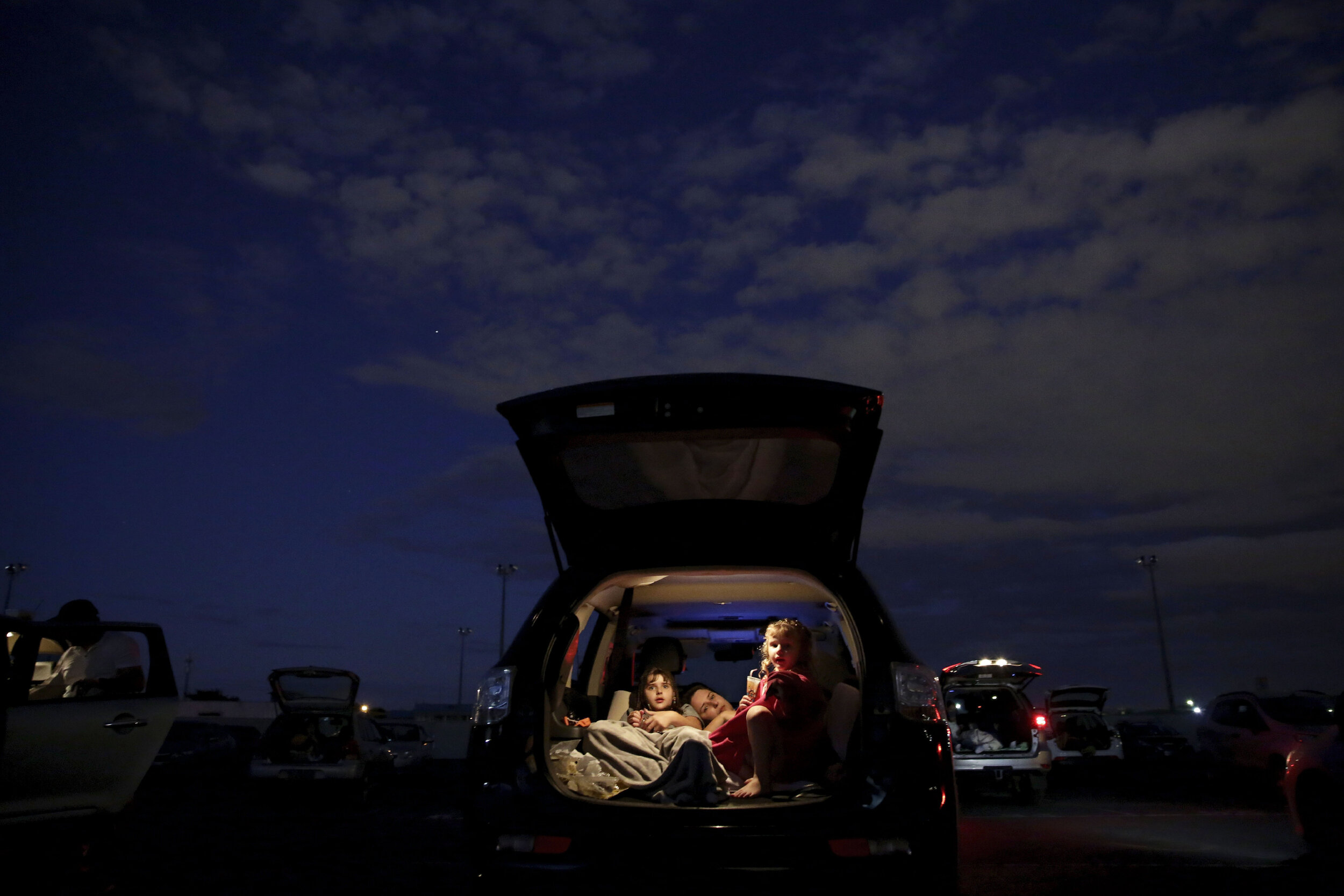  A family watches a movie from the back of their car at a drive-in where motorists must leave one space empty between them amid the new coronavirus pandemic in Brasilia, Brazil, Saturday, May 23, 2020. (AP Photo/Eraldo Peres) 