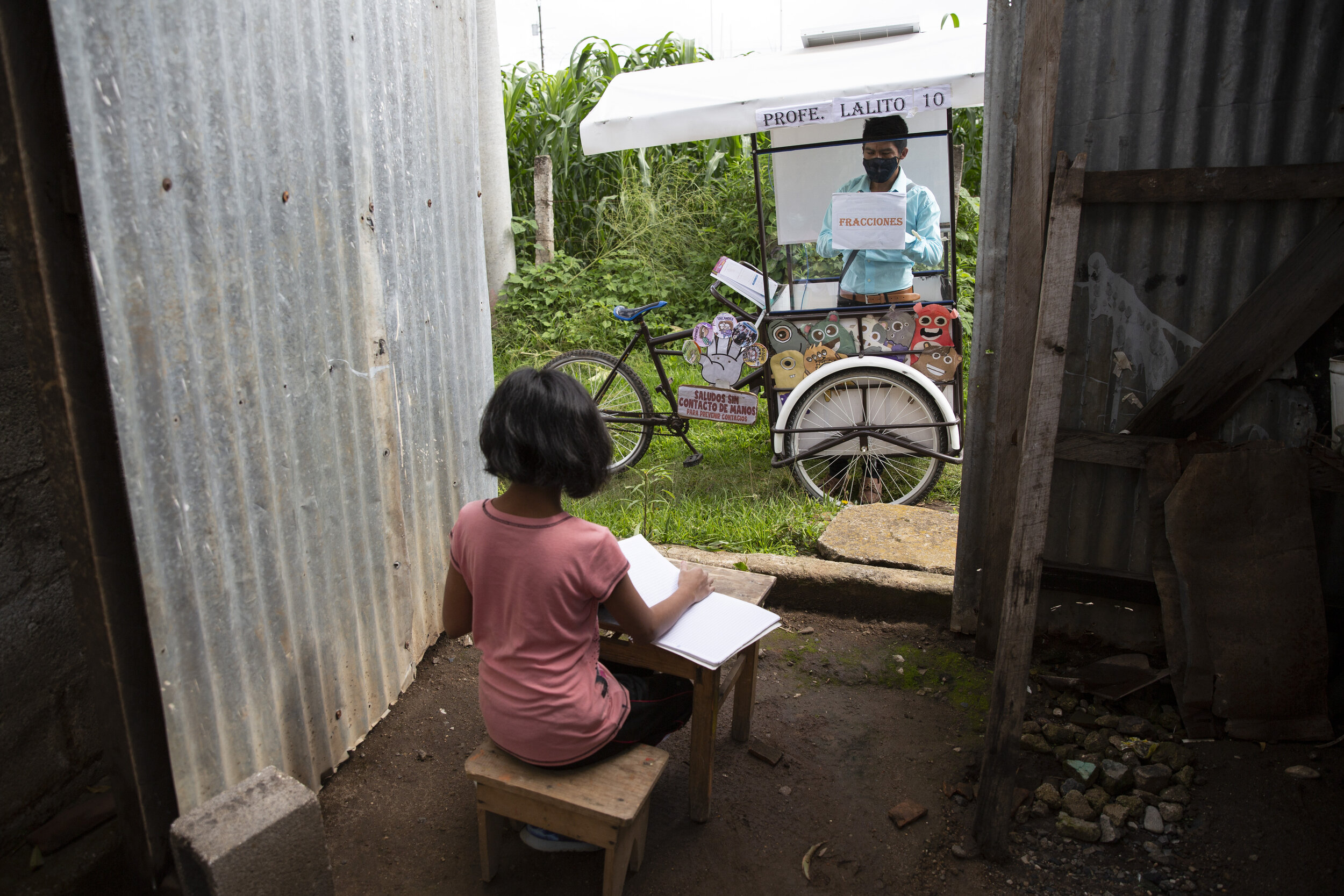  Gerardo Ixcoy teaches 12-year-old student Paola Ximena Conoz about fractions from his mobile classroom, parked outside her home in Santa Cruz del Quiche, Guatemala, Wednesday, July 15, 2020. Each day the 27-year-old sets out pedaling among the cornf