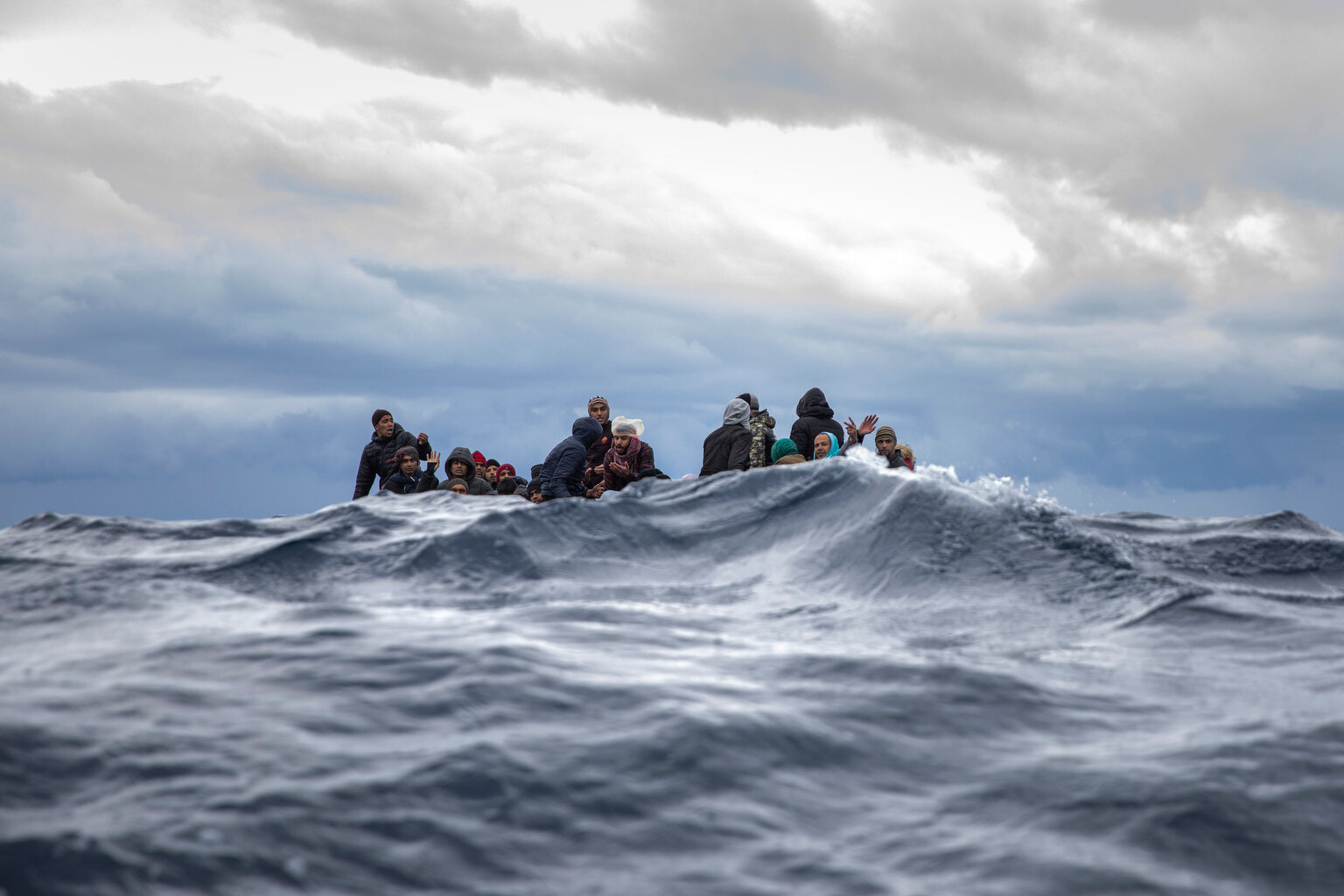  Men from Morocco and Bangladesh react on an overcrowded wooden boat, as aid workers of the Spanish NGO Open Arms approach them in the Mediterranean Sea, international waters, off the Libyan coast, Friday, Jan. 10, 2020. (AP Photo/Santi Palacios) 