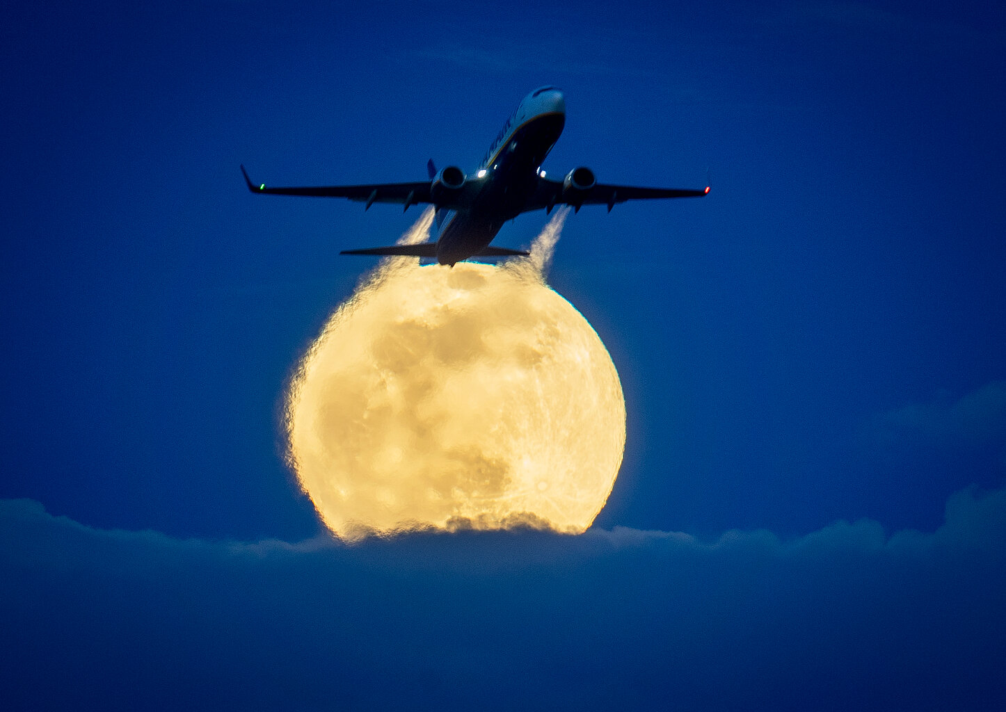  An aircraft passes the rising full moon that breaks through the clouds at the airport in Frankfurt, Germany, Monday, March 9, 2020. (AP Photo/Michael Probst) 