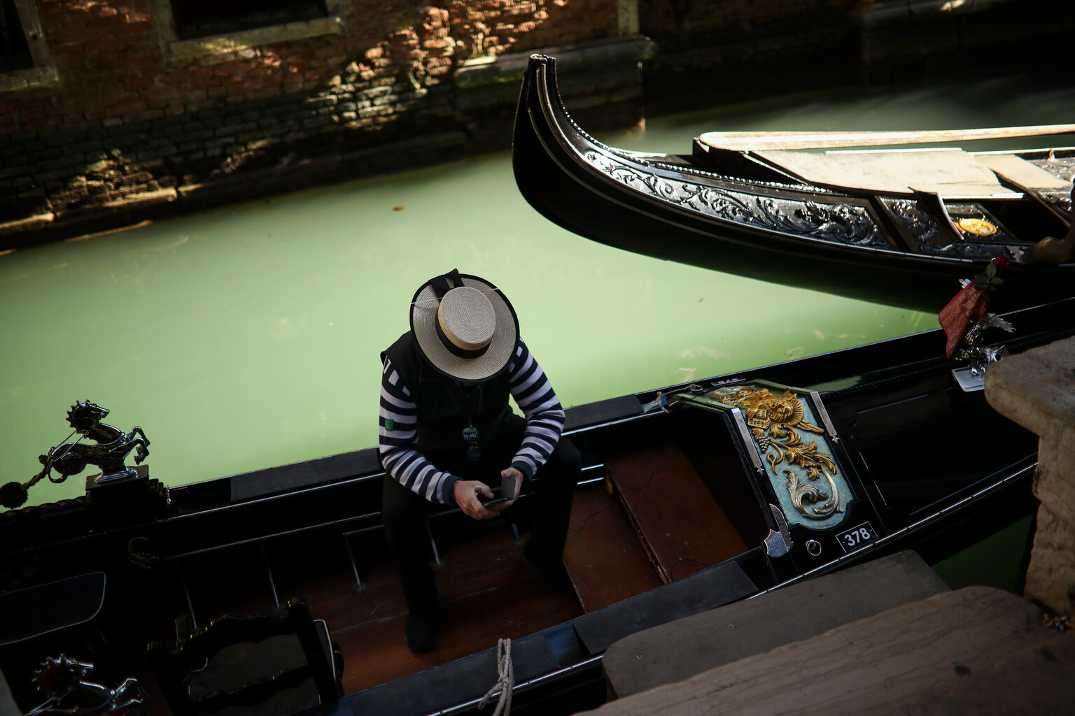  A gondolier looks at his smartphone as he waits for clients in Venice, Italy, Friday, Feb. 28, 2020. (AP Photo/Francisco Seco) 