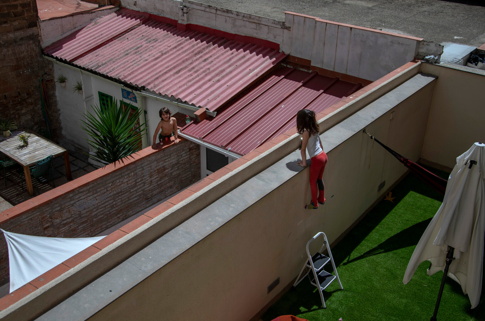  Gala, 7, speaks with her friend and classmate Oliver, 6, as they jump on the wall on their courtyard in Barcelona, Spain, Wednesday, April 29, 2020 as the lockdown to combat the spread of coronavirus continues. (AP Photo/Emilio Morenatti) 