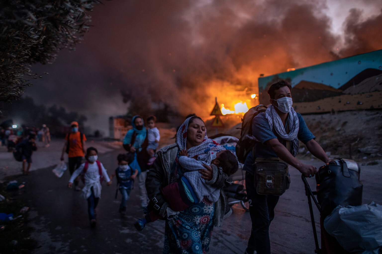  Refugees and migrants carrying their belongings flee a fire burning at Moria camp, on Lesbos island, Greece, Wednesday, Sept. 9, 2020. (AP Photo/Petros Giannakouris) 