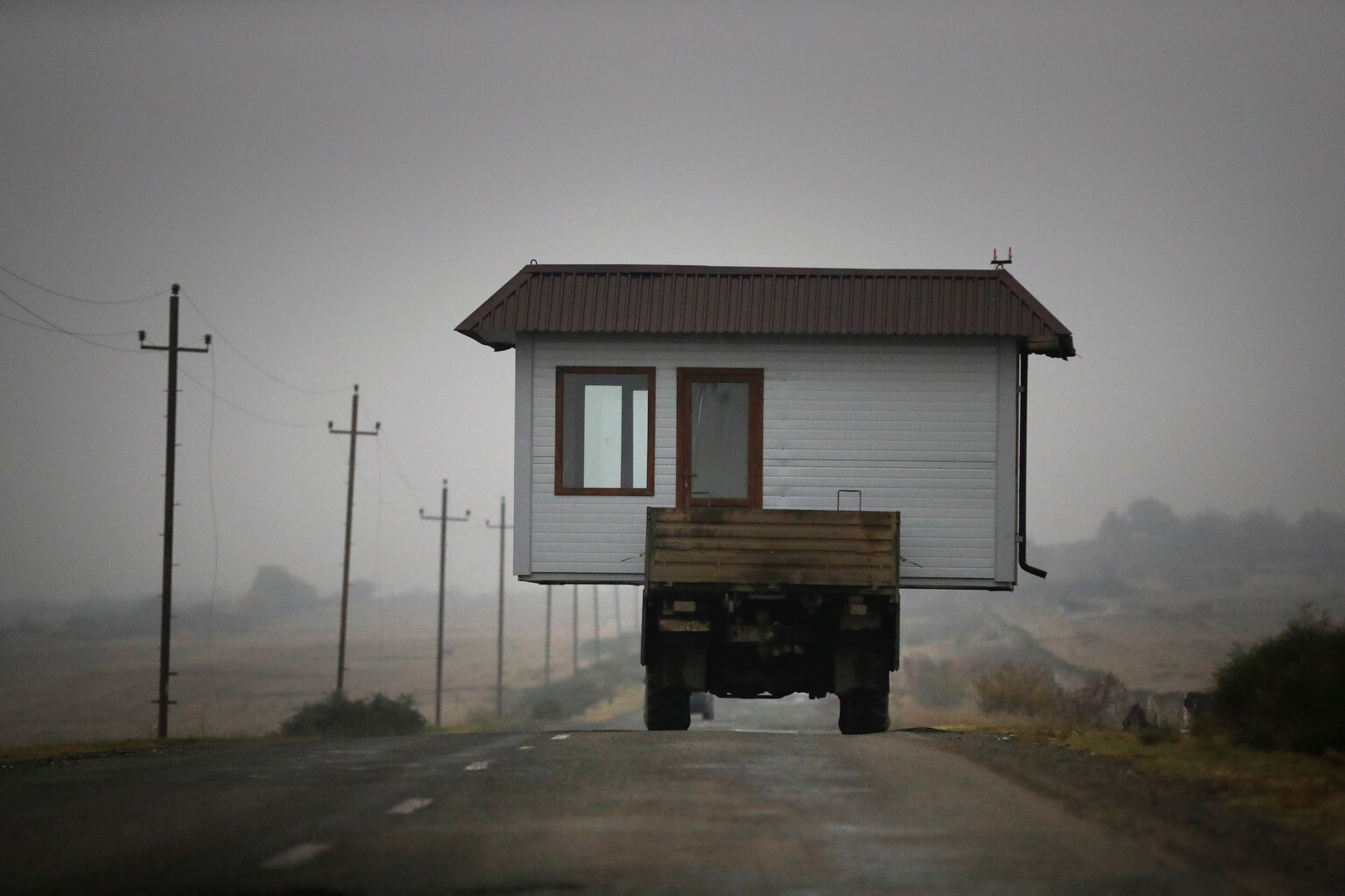  A family drives a truck loaded with a small house along a highway as they leave their home village in the separatist region of Nagorno-Karabakh, Wednesday, Nov. 18, 2020. (AP Photo/Sergei Grits) 