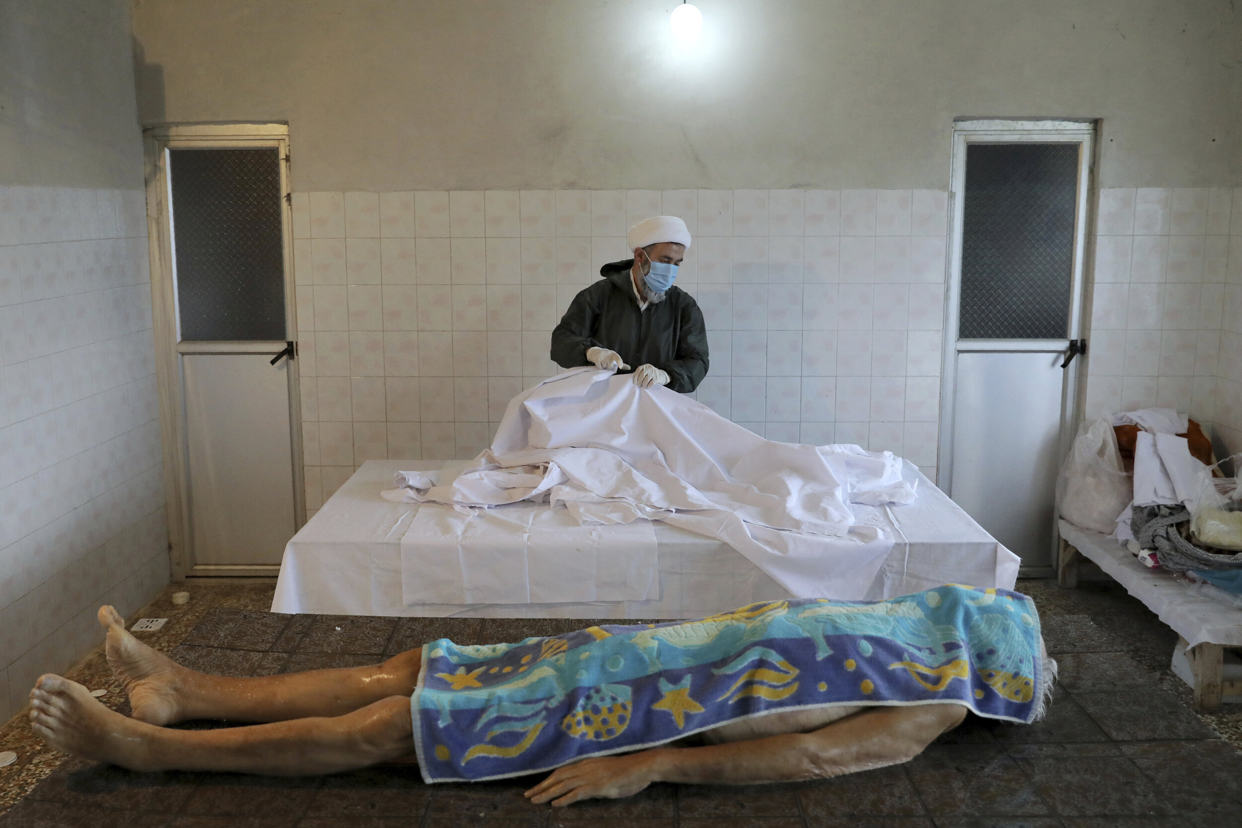  A cleric wearing protective clothing prepares the body of a man who died from COVID-19 for a funeral at a cemetery in the outskirts of the city of Ghaemshahr, in northern Iran, Thursday, Dec. 17, 2020. (AP Photo/Ebrahim Noroozi) 