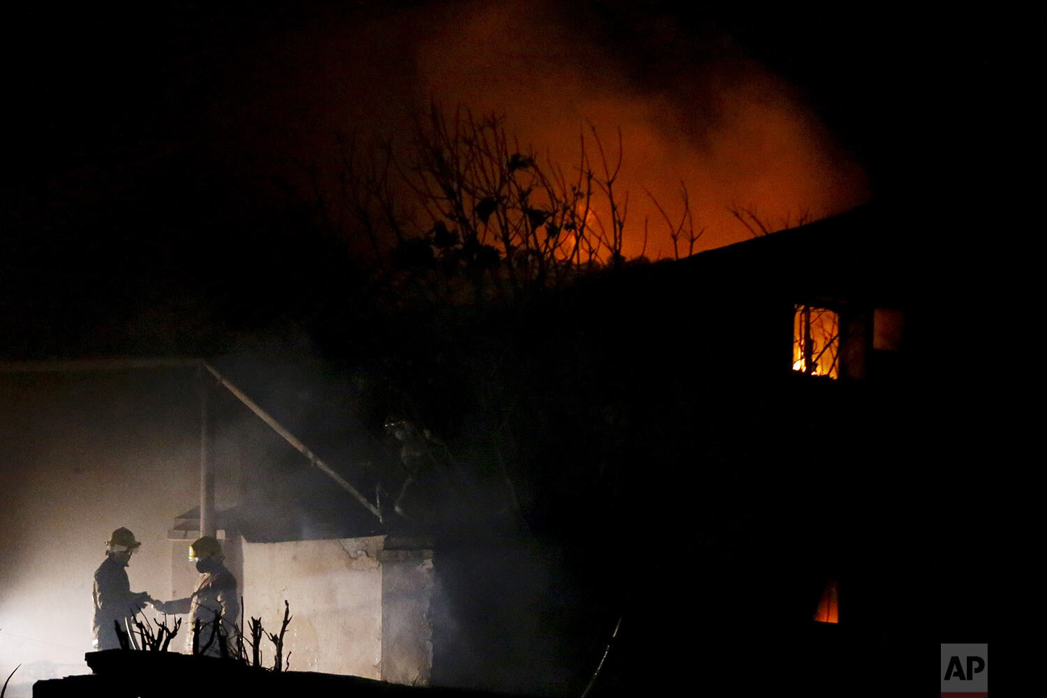 Firefighters work the scene of a fire at La Chacarita neighborhood on Christmas Eve, in Asunción, Paraguay, Friday, Dec. 25, 2020. (AP Photo/Cesar Olmedo)