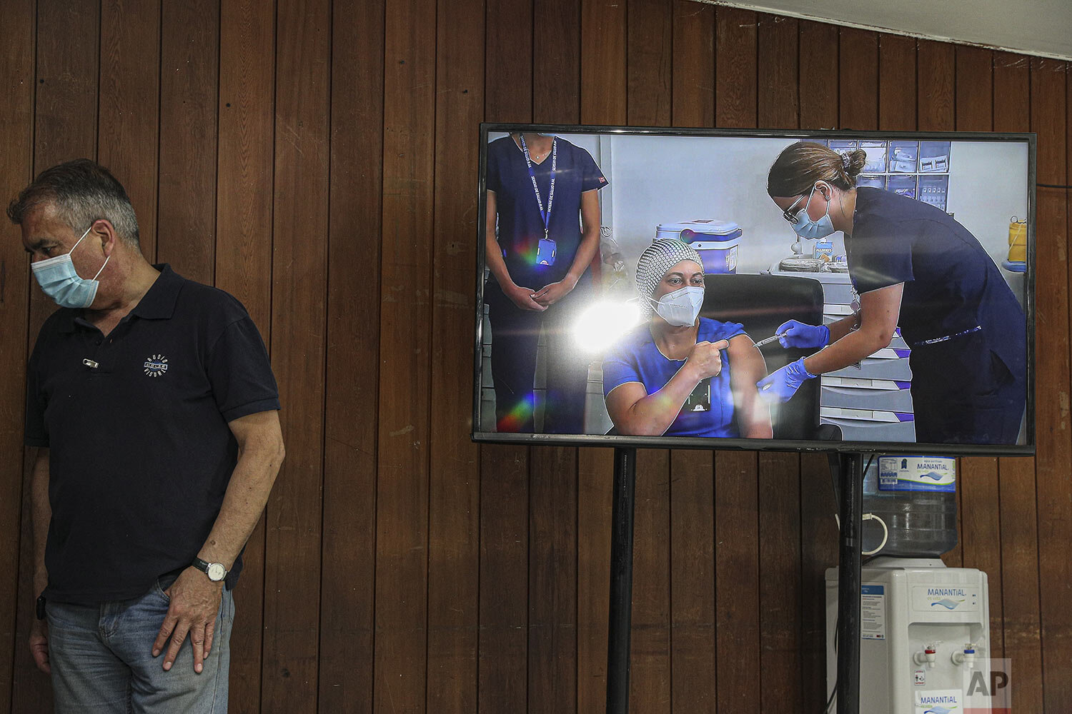 A monitor shows a live video image of nurse Zulema Riquelme getting the first shot of the COVID-19 vaccine at the Metropolitan Hospital in Santiago, Chile, Thursday, Dec. 24, 2020, after the first batches of Pfizer vaccines arrived. (AP Photo/Esteban Felix)
