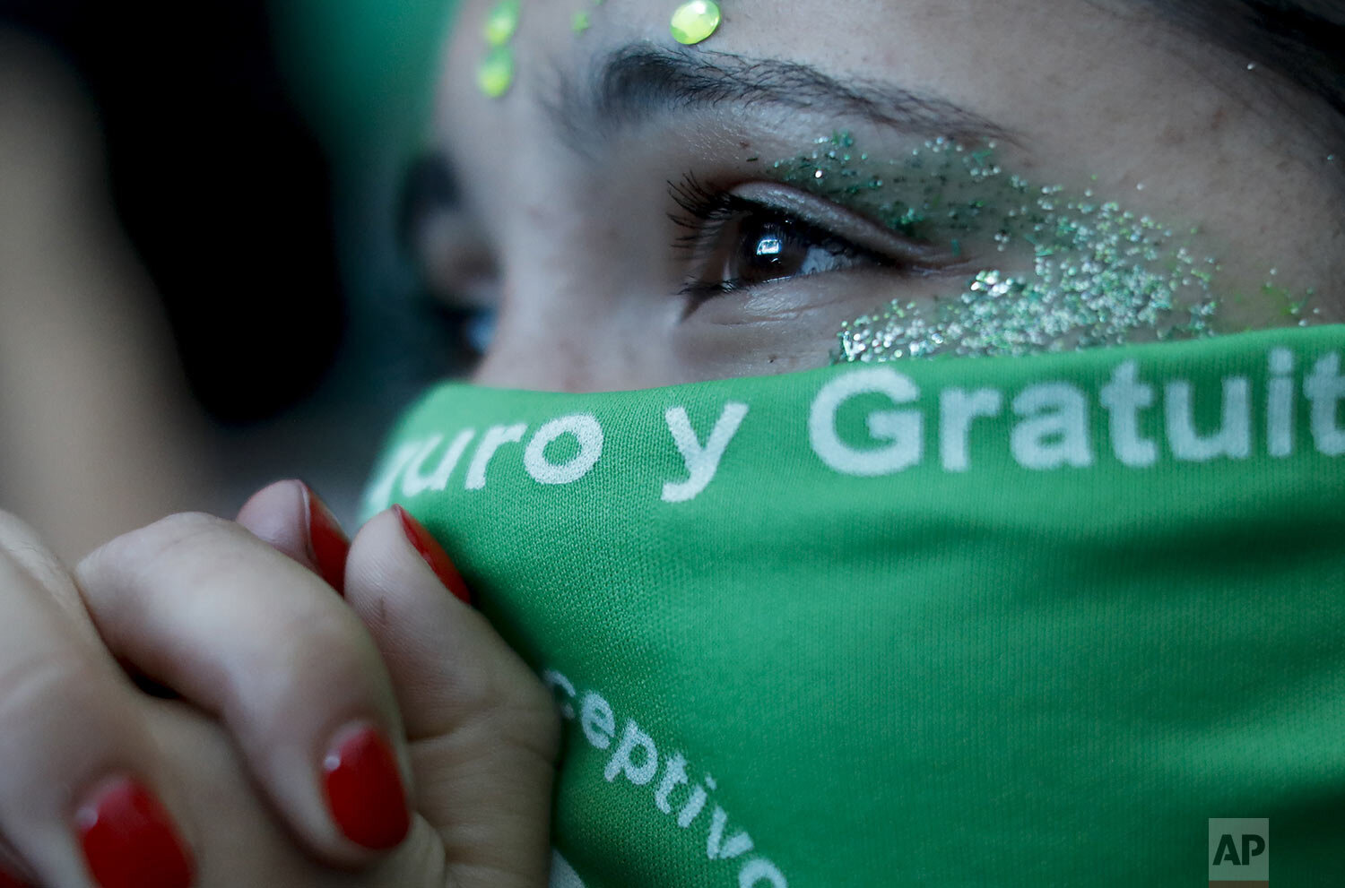 An abortion-rights activist watches a screen showing live video of lawmakers debating to decriminalize abortion, outside Congress in Buenos Aires, Argentina, Friday, Dec. 11, 2020, before voting in favor of the bill. Days later the Senate also voted in favor, guaranteeing abortion up to the 14th week of pregnancy and beyond that in cases of rape or when a woman’s health is at risk. (AP Photo/Natacha Pisarenko)
