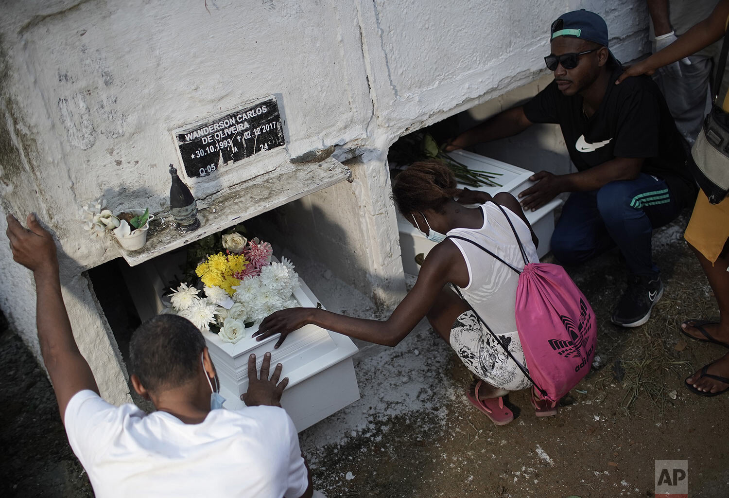 Relatives of cousins Emily Victoria Silva dos Santos, 4, and Rebeca Beatriz Rodrigues dos Santos, 7, kneel by their coffins as they bury the cousins in Duque de Caxias, Rio de Janeiro state, Brazil, Saturday, Dec. 5, 2020. Grieving families held funerals for the girls killed by bullets while playing outside their homes. (AP Photo/Silvia Izquierdo)