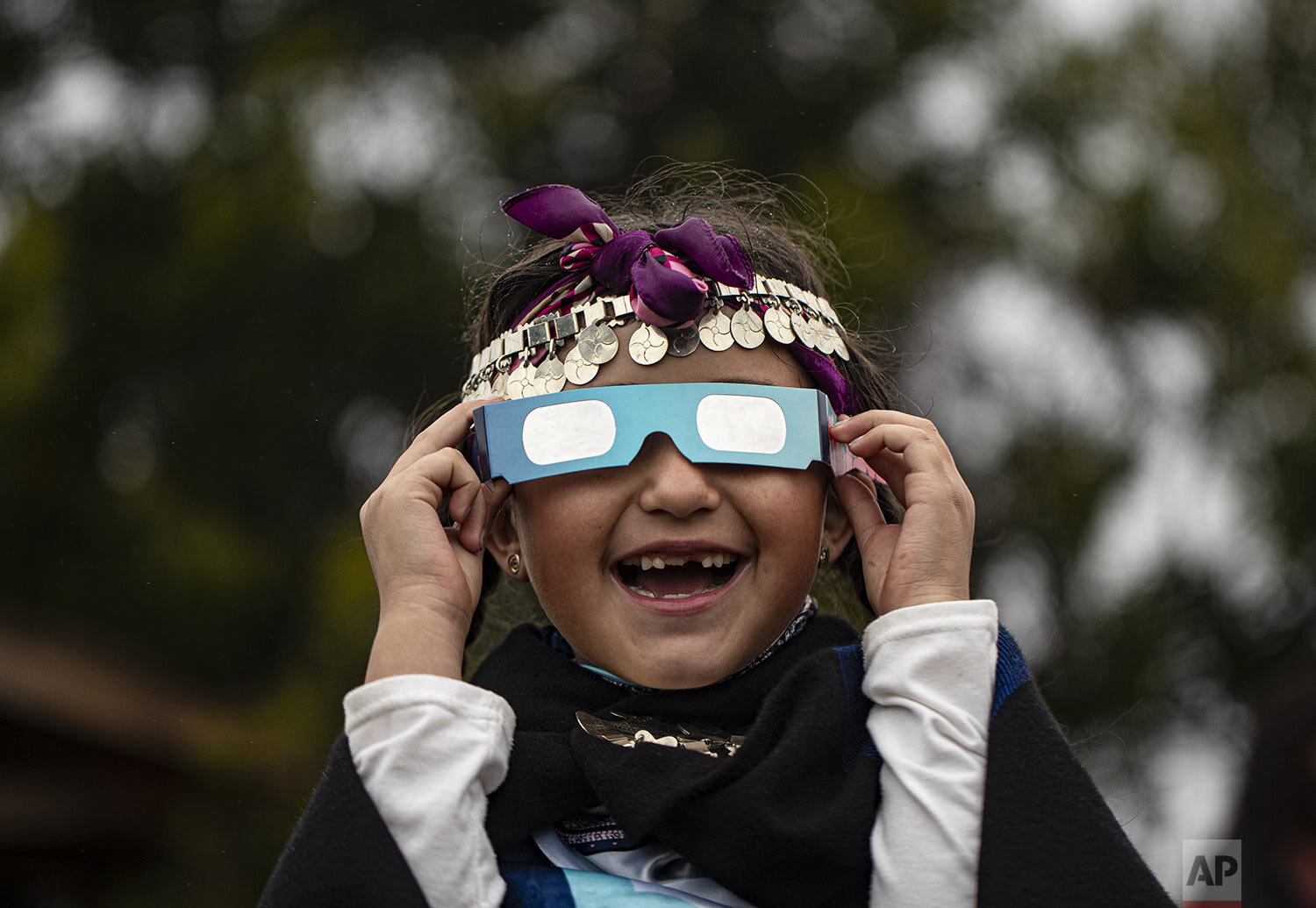 Magdalena Nahuelpan, a Mapuche Indigenous girl, uses special glasses to look at a total solar eclipse in Carahue, La Araucania, Chile, Monday, Dec. 14, 2020. (AP Photo/Esteban Felix)