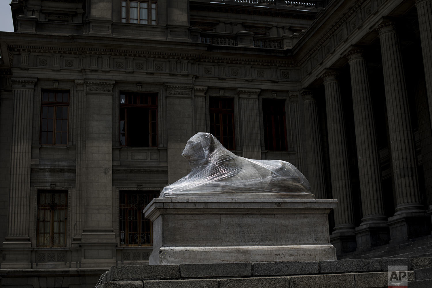 A lion statue outside the Palace of Justice is wrapped in plastic during maintenance in Lima, Peru, Tuesday, Dec. 1, 2020. Monuments were practically spared by protesters decrying a parliamentary coup in early November when Congress voted to oust ex-President Martín Vizcarra. (AP Photo/Rodrigo Abd)