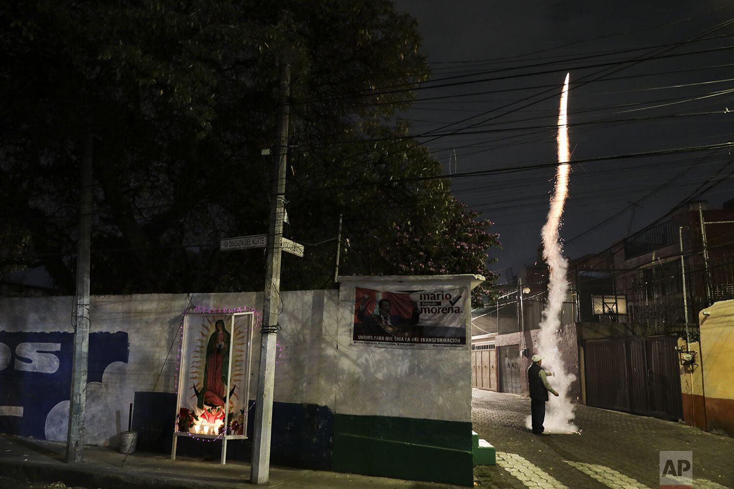 A man lights a firecracker next to an altar in honor of the Virgin of Guadalupe in Mexico City, Friday Dec. 11, 2020. Nationwide, devotees of the Virgin make a pilgrimage to the Basilica in honor of her Dec. 12 feast day, but the Catholic Church announced the closure of the Basilica for this year's pilgrimage due to the coronavirus pandemic. (AP Photo/Eduardo Verdugo)