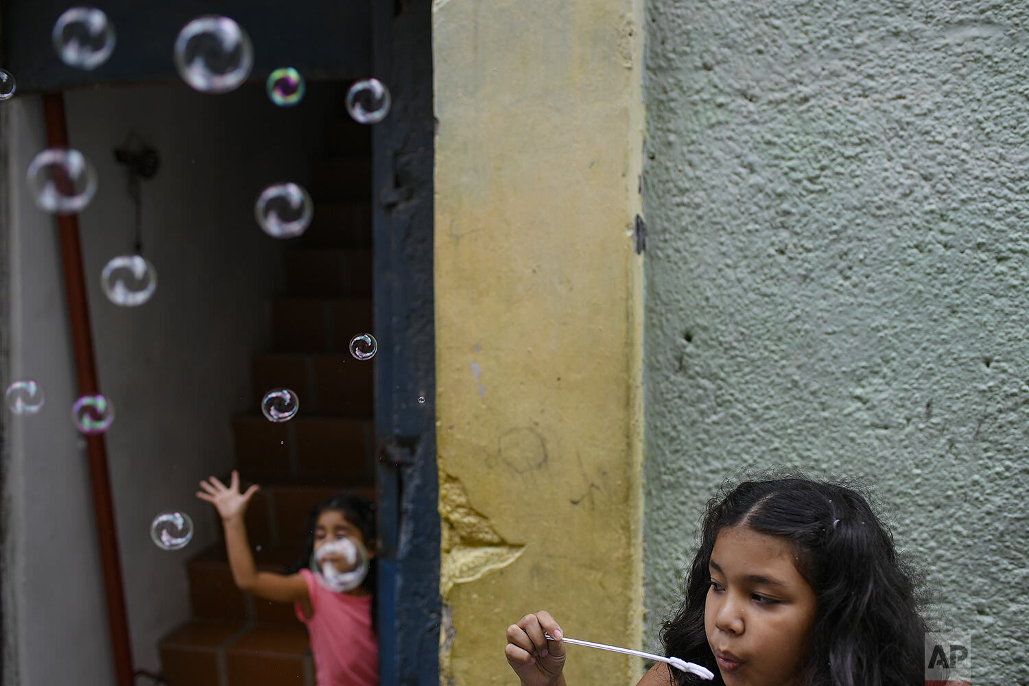 Sisters play with soap bubbles in the Catia neighborhood on Christmas Day in Caracas, Venezuela, Friday, Dec. 25, 2020, amid the new coronavirus pandemic. (AP Photo/Matias Delacroix)