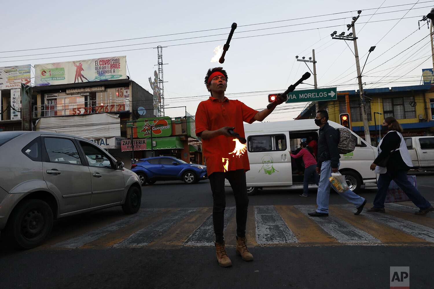 Willian Ramirez Lopez juggles fire to earn tips from passing motorists in Ecatepec, Mexico State, where a state mandate calls for nonessential businesses to close at 5 p.m., to help slow the spread of COVID-19 on the outskirts of Mexico City, Monday, Dec. 14, 2020. (AP Photo/Rebecca Blackwell)