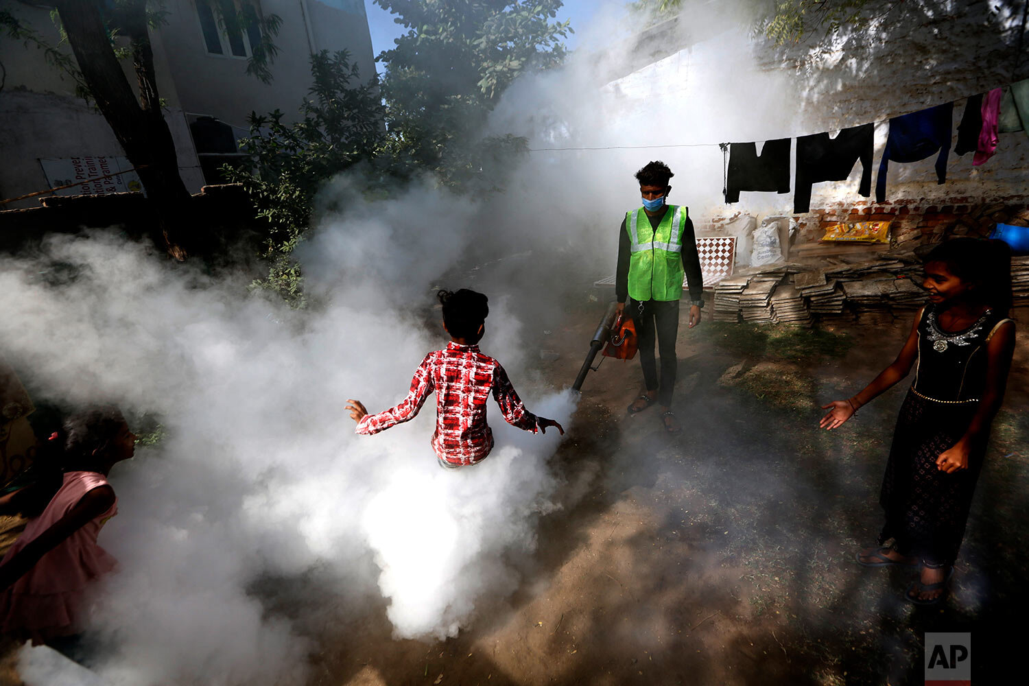  A boy plays in smoke from fumigation being carried out by a municipal worker at a residential area in Ahmedabad, India, Thursday, Dec. 3, 2020. (AP Photo/Ajit Solanki) 