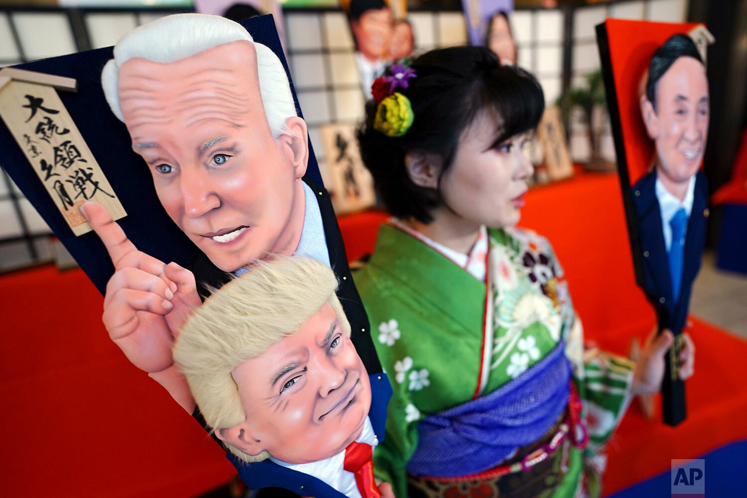  An employee of Kyugetsu, a Japanese traditional doll company, poses with special "hagoita" battledores featuring President-elect Joe Biden with President Donald Trump and Japanese Prime Minister Yoshihide Suga Thursday, Dec. 3, 2020, in Tokyo.  (AP 