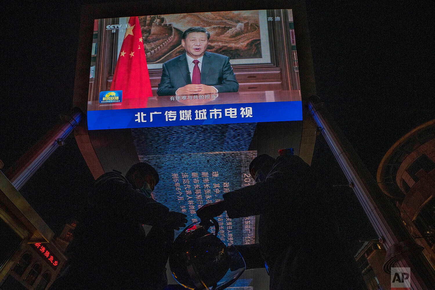  Security guards change shift under a screen showing Chinese President Xi Jinping delivering a speech for the evening news broadcast in Beijing Thursday, Dec. 31, 2020.  (AP Photo/Ng Han Guan) 